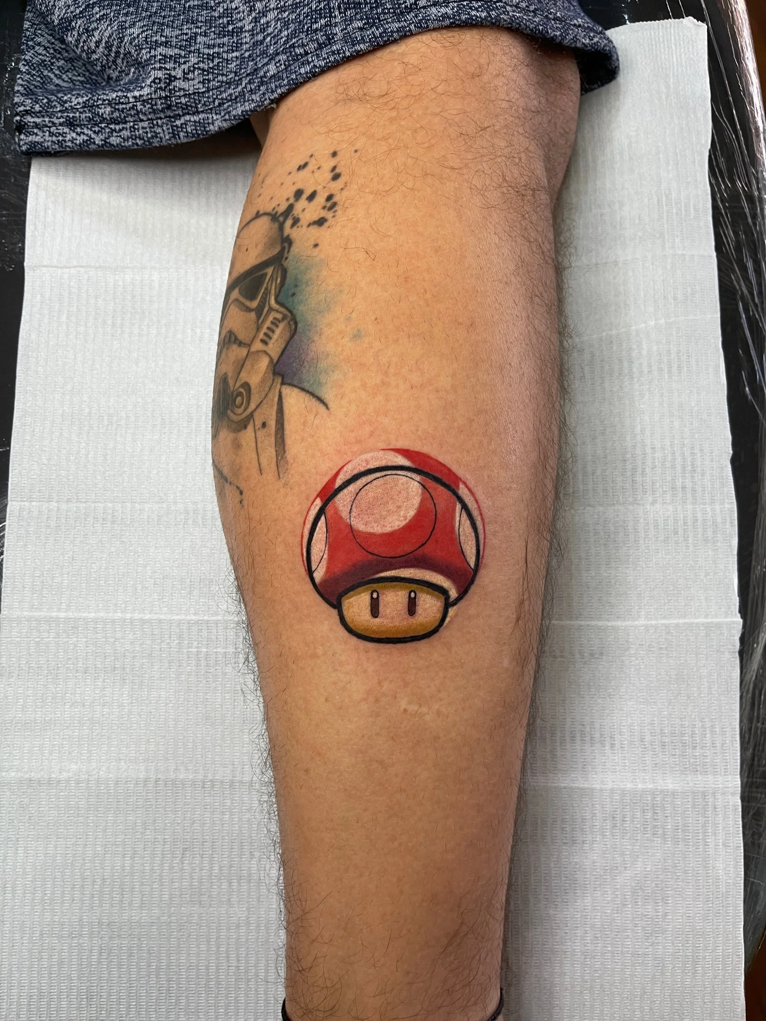 Red power-up mushroom tattoo on calf in neo-traditional style