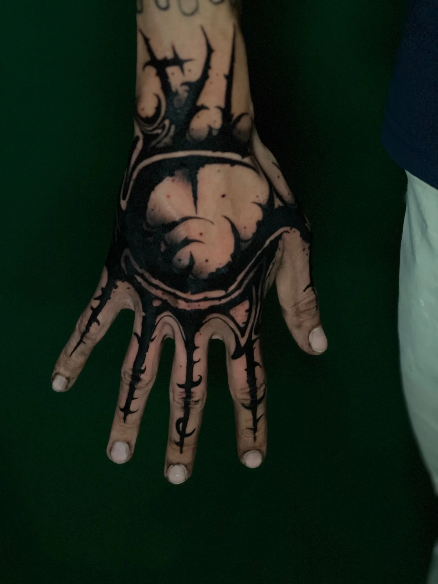 Bold blackwork hand tattoo with eye motif and thorned linework