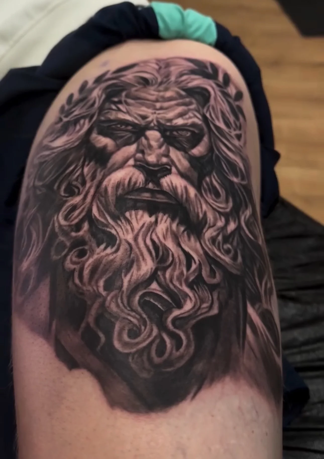 Black and grey realism Zeus portrait tattoo on upper arm
