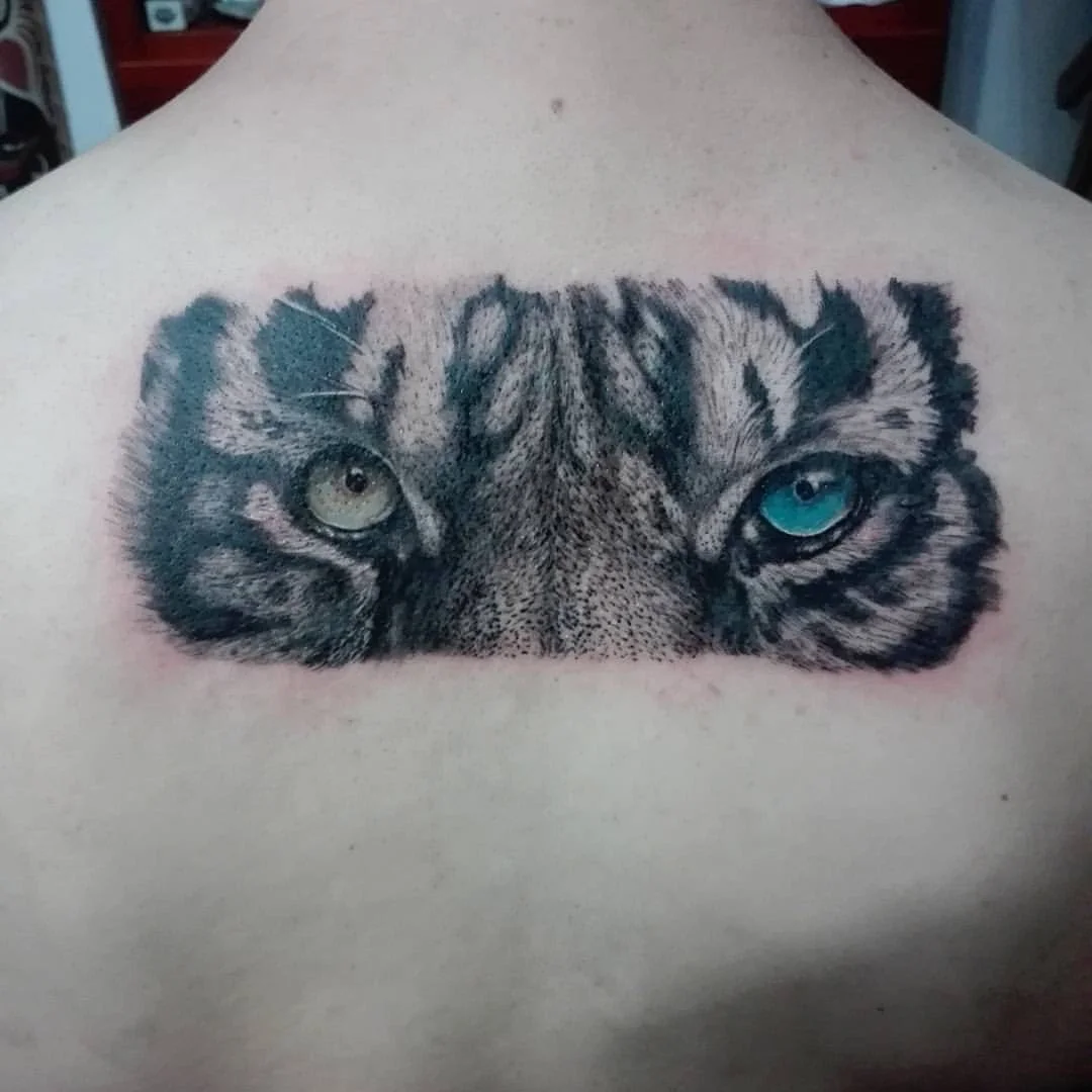 Realistic tiger eyes tattoo with heterochromatic irises on upper back