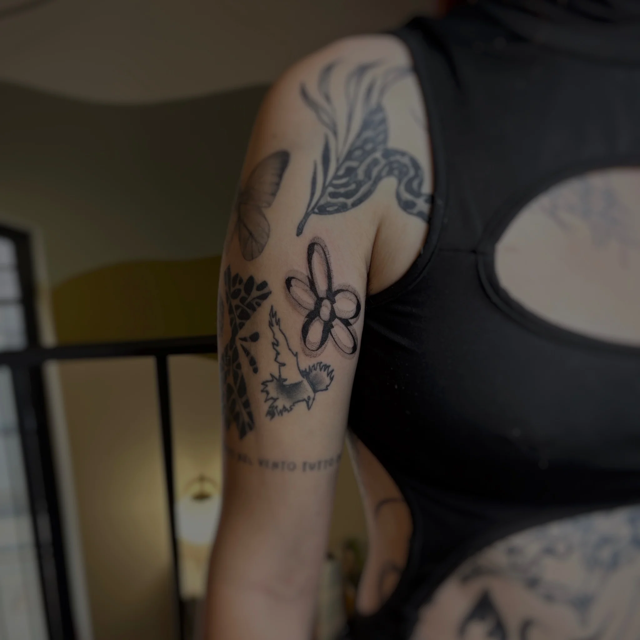 Patchwork black ink tattoo collection on upper arm and forearm