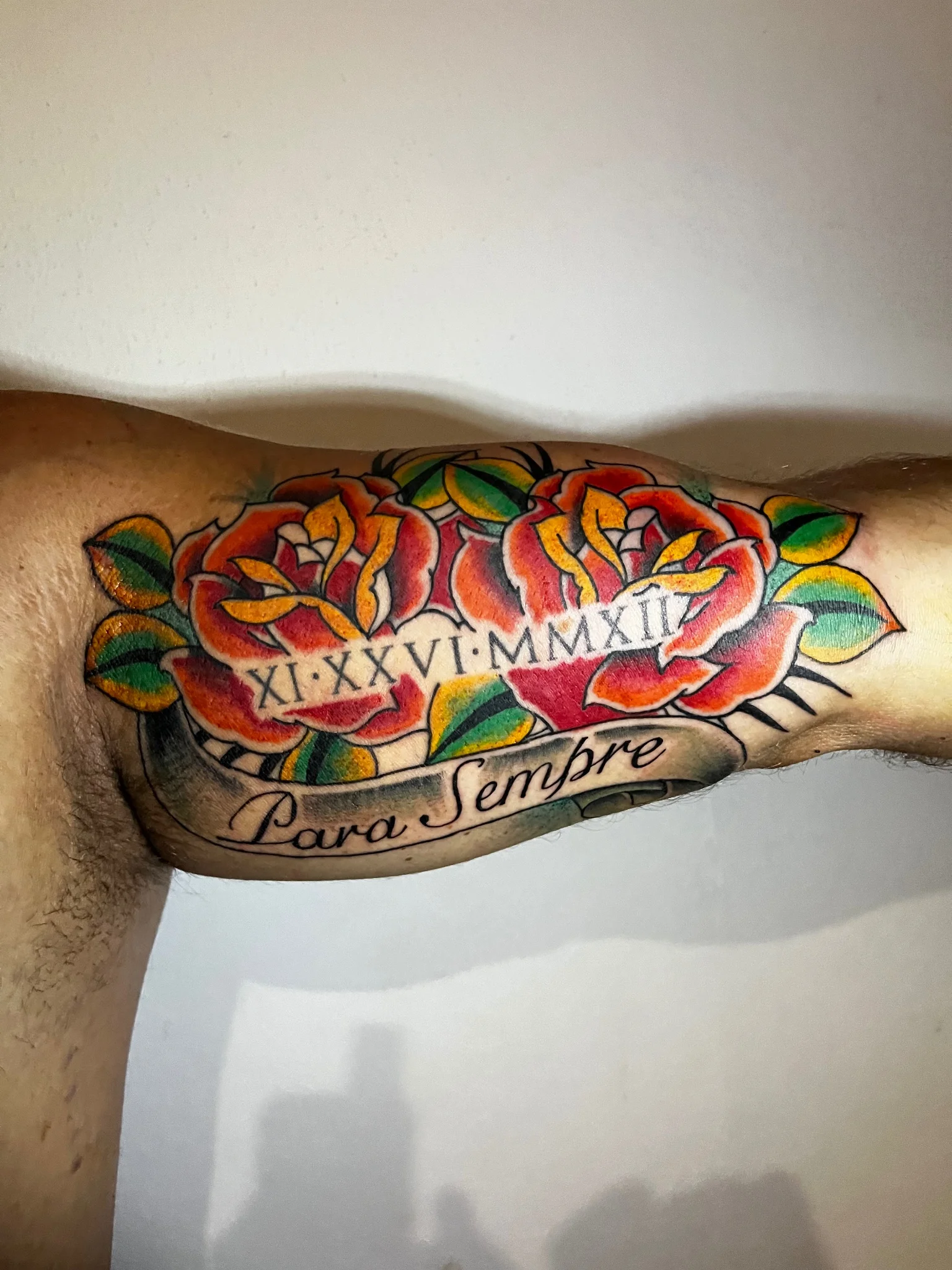 American traditional rose tattoo with roman numerals and banner on inner arm