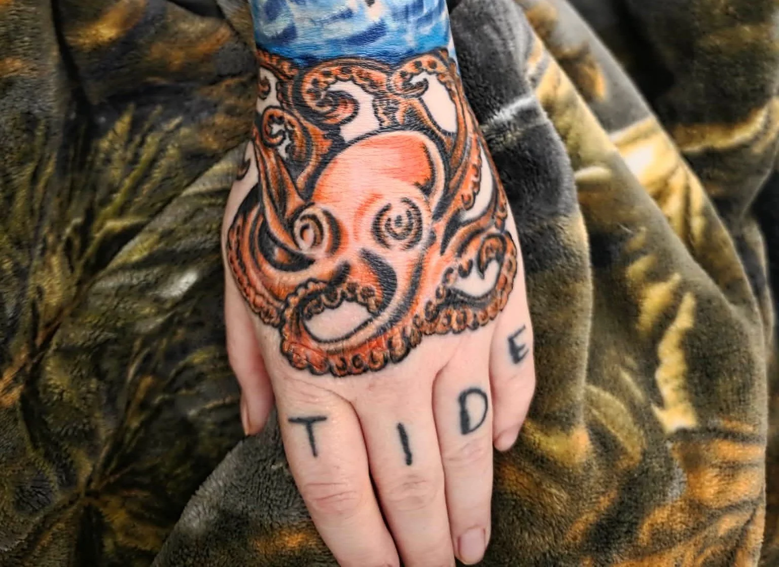 Neo-traditional color octopus tattoo on hand with finger lettering