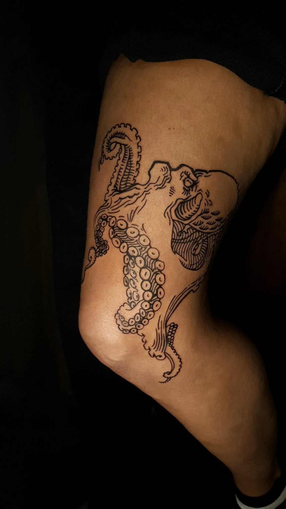 Black ink Japanese-style octopus tattoo wrapping around the knee