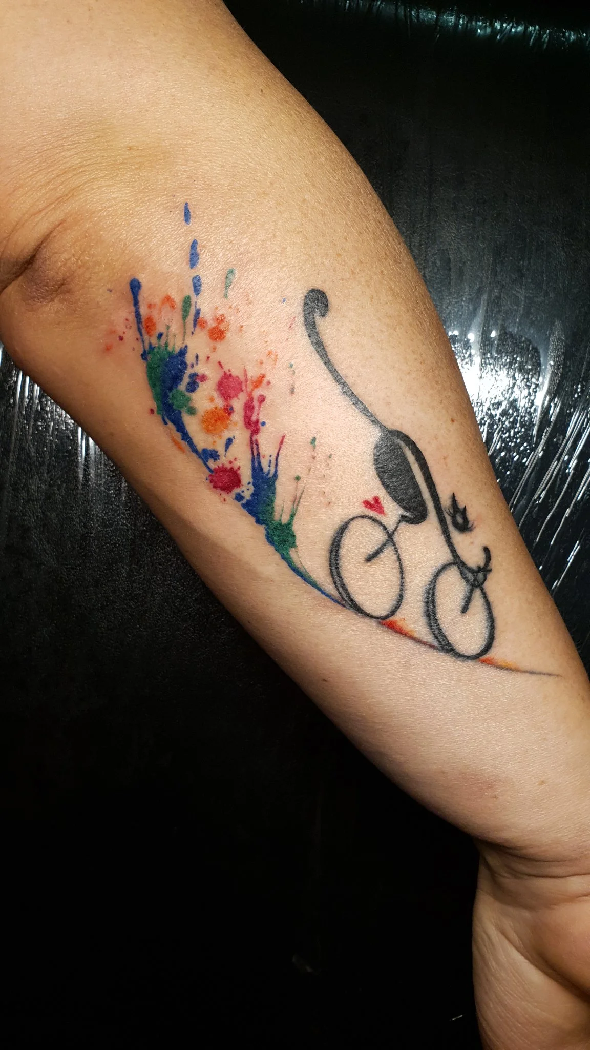 Watercolor music note and headphones tattoo on forearm