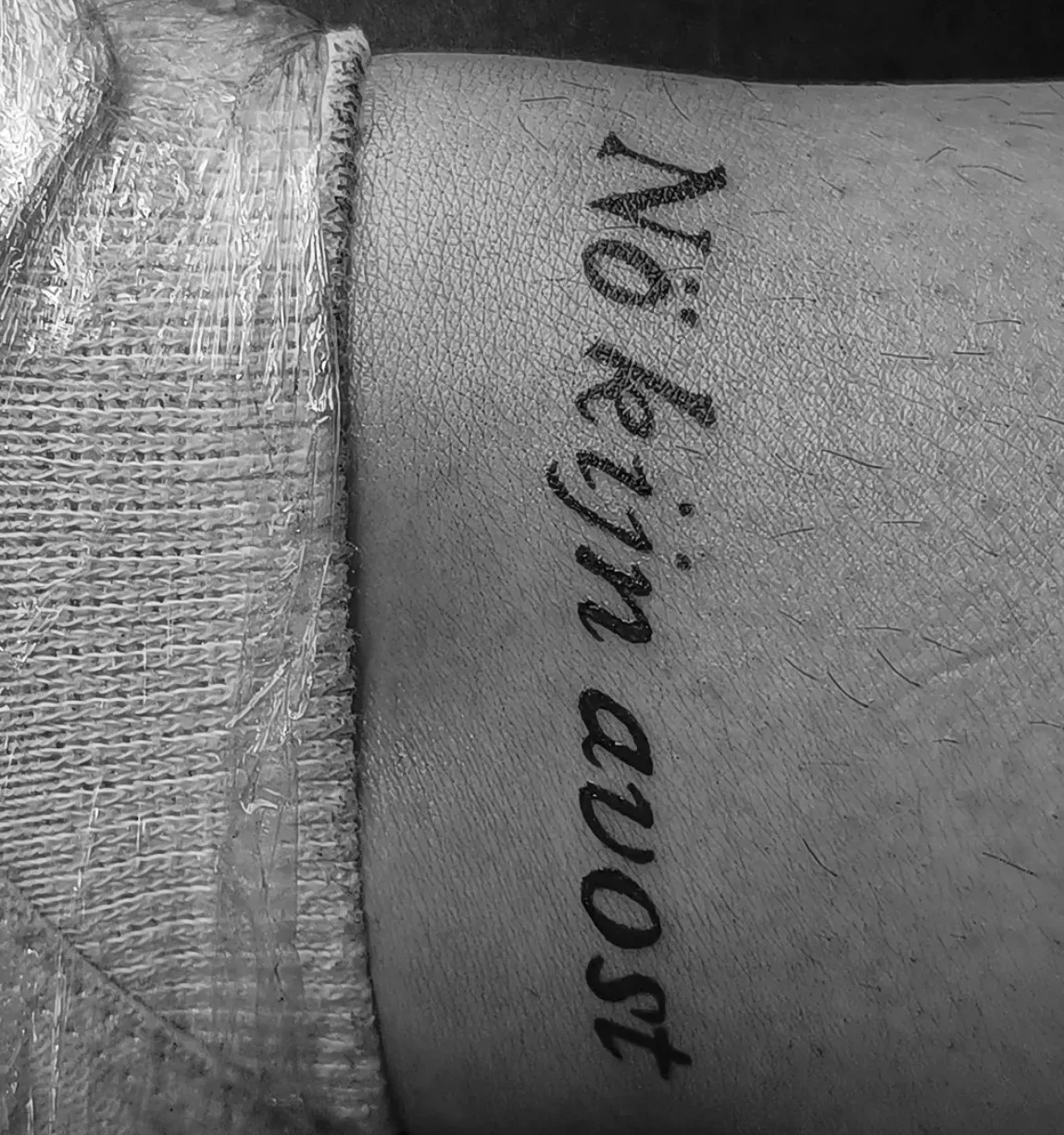 Black script lettering tattoo reading 'Nothing avost' on wrist