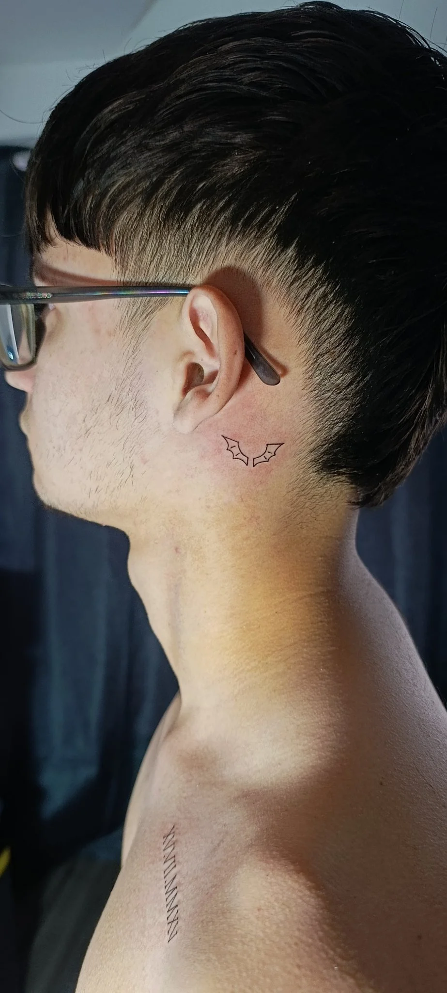 Fine line bat wings tattoo behind the ear with spine lettering