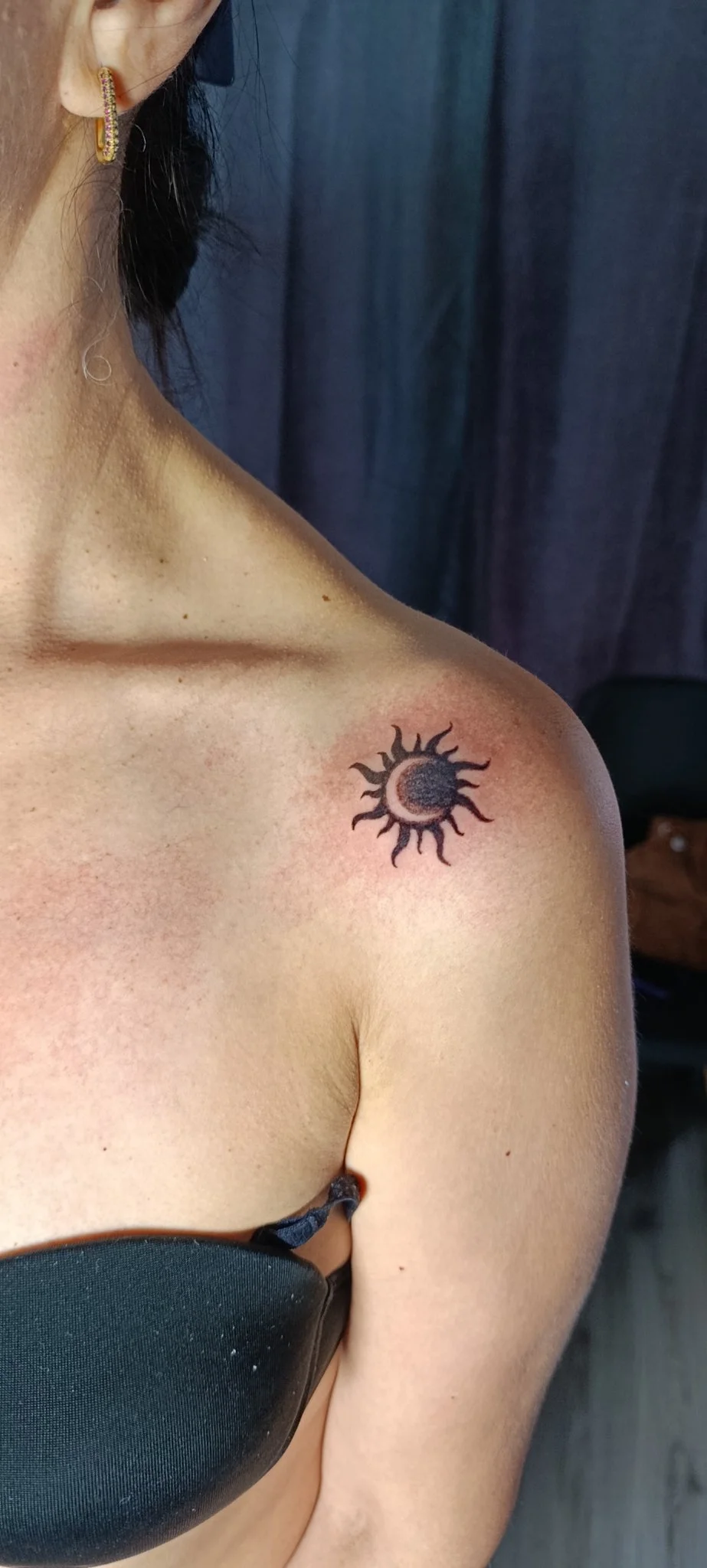 Blackwork sun and moon eclipse tattoo on shoulder