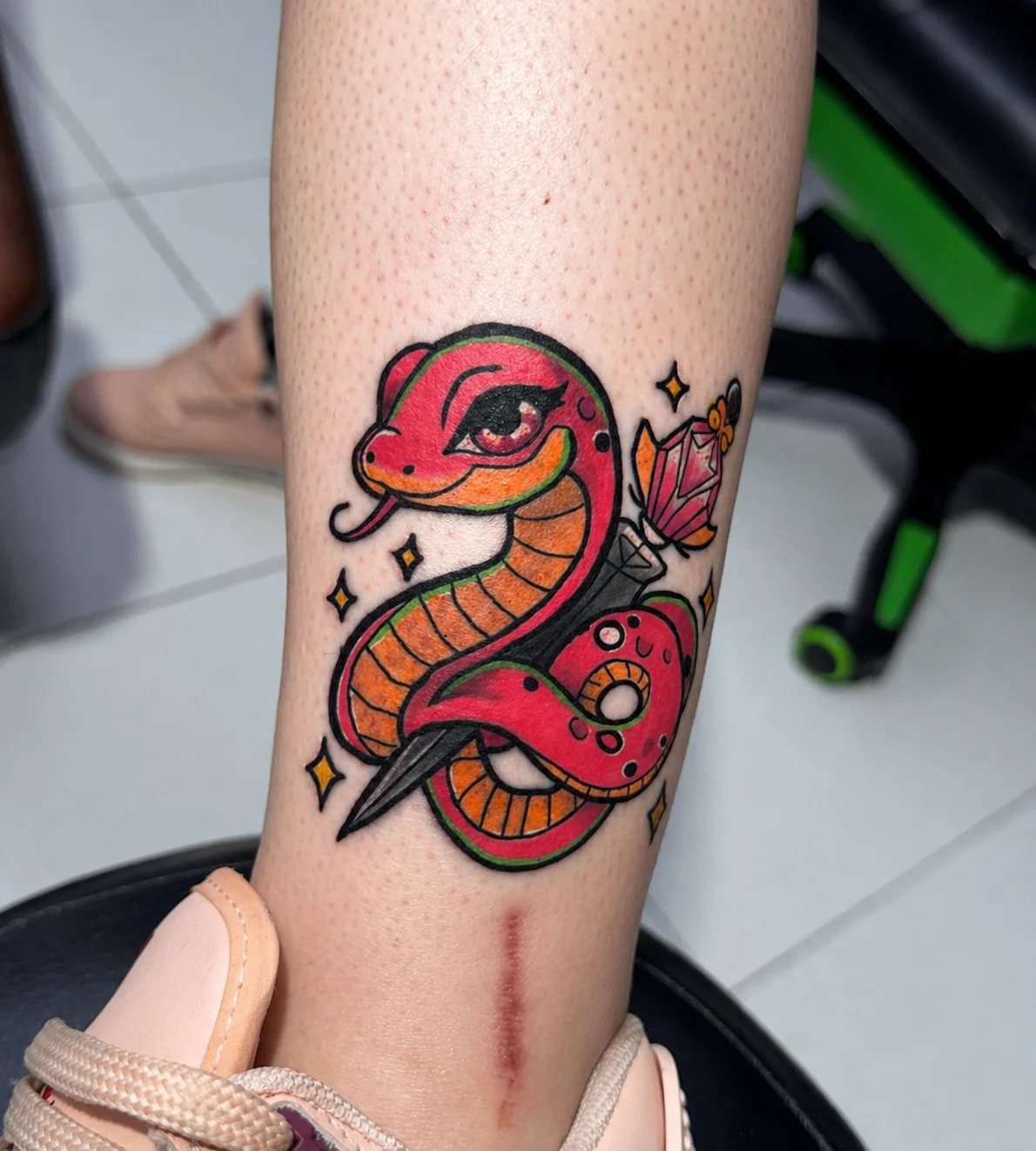 Neo-traditional snake and dagger tattoo on lower leg