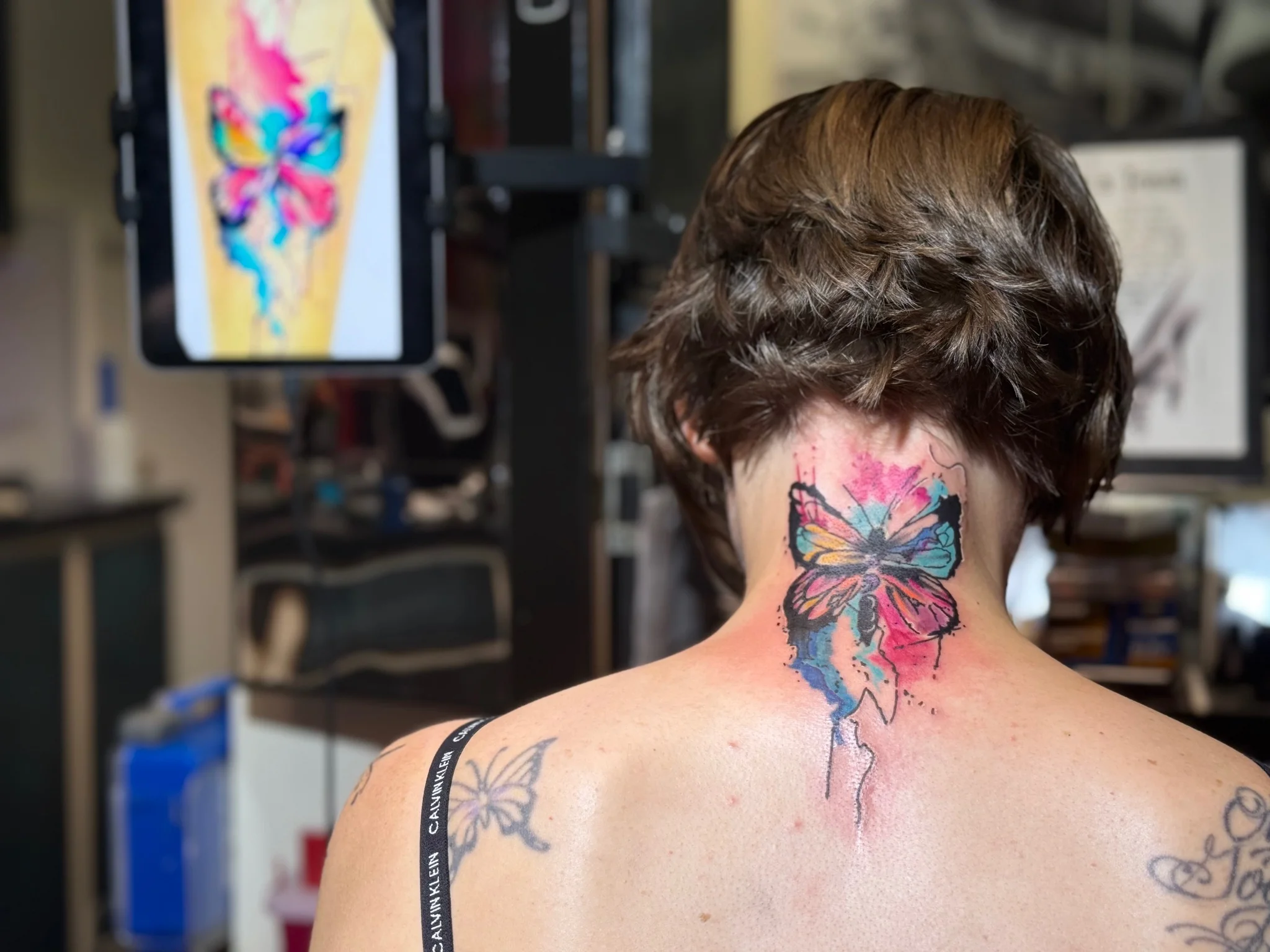 Colorful watercolor butterfly tattoo on the back of neck
