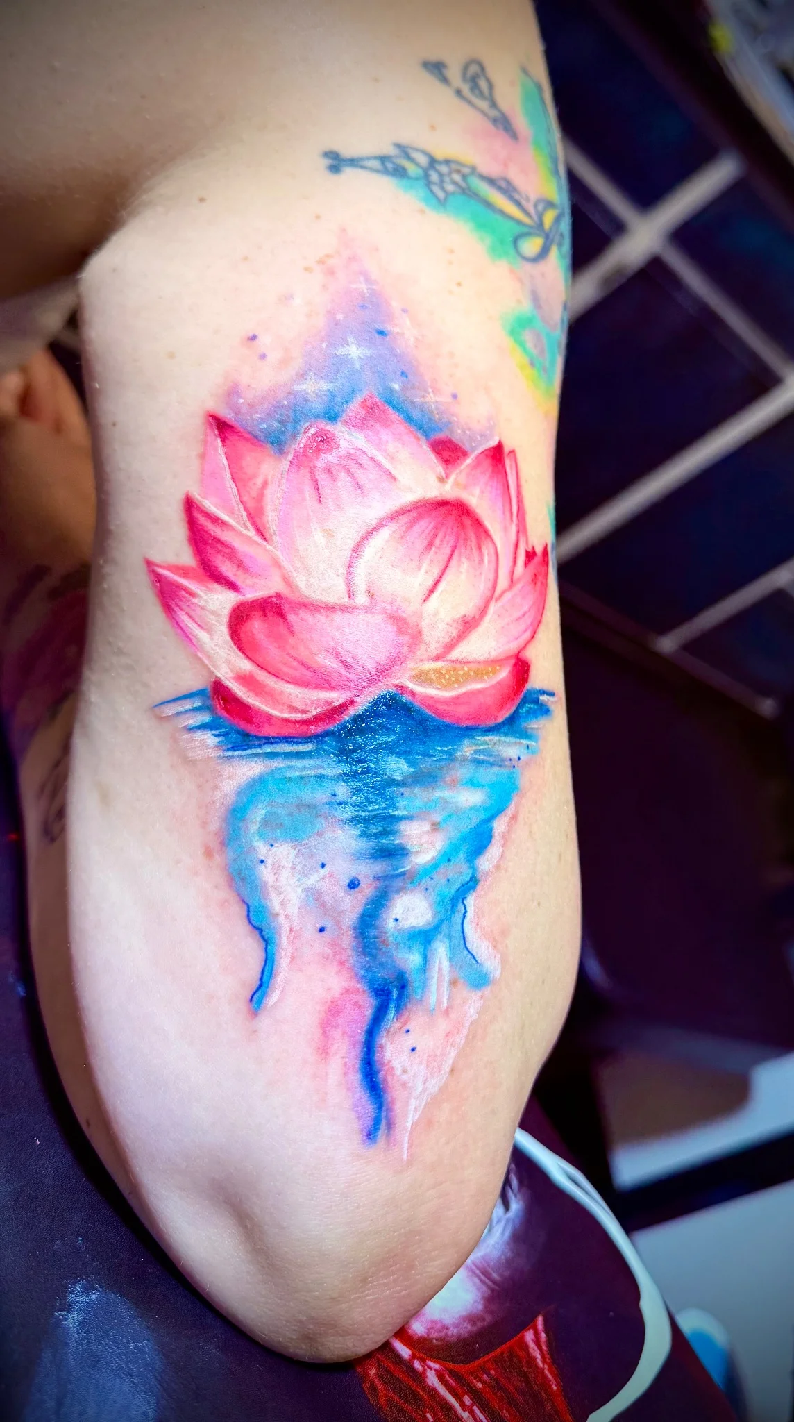 Watercolor lotus flower tattoo with water reflection on upper arm
