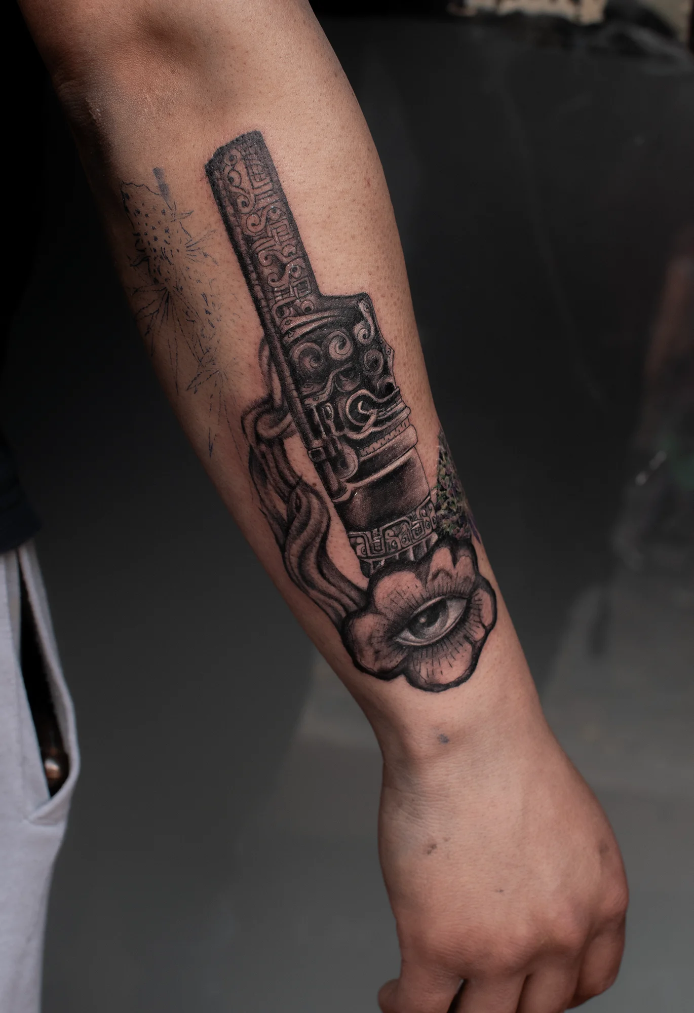 Black and grey Mesoamerican idol totem tattoo on forearm