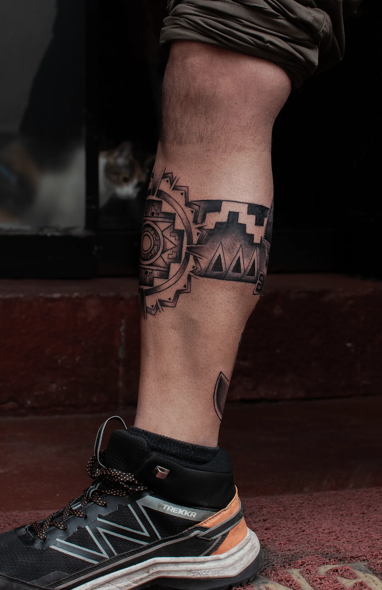 Black geometric armband tattoo with mandala detail on calf