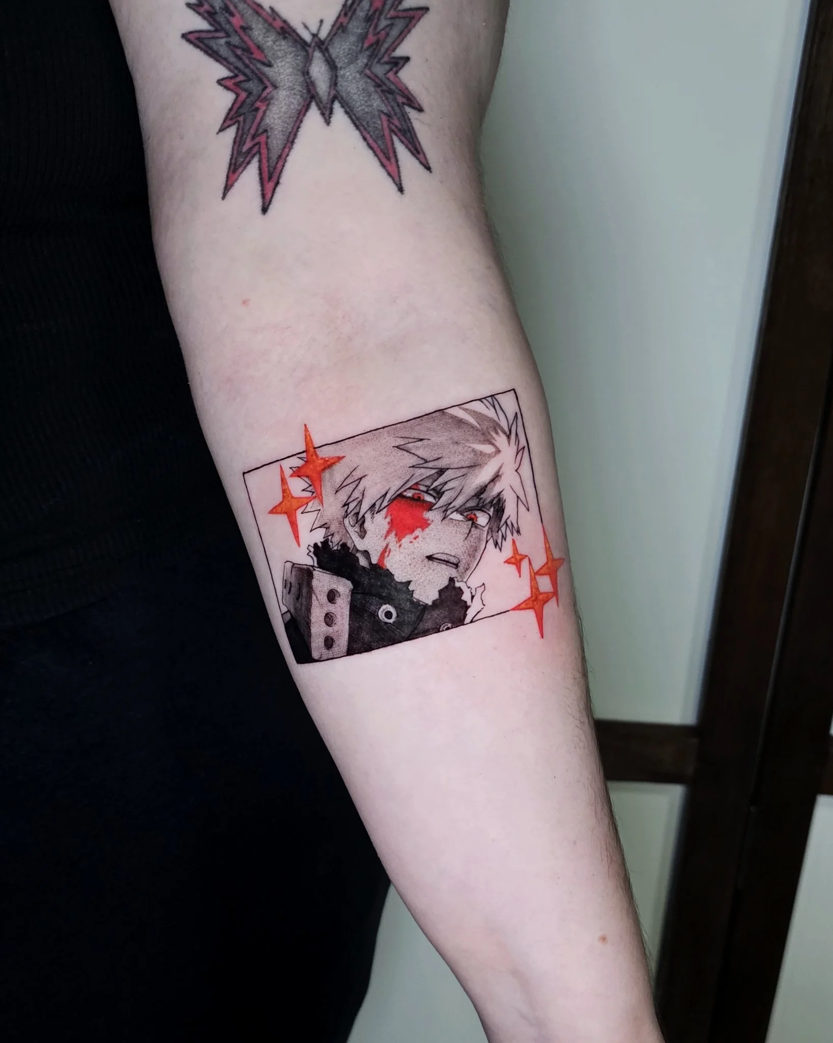 Anime manga panel tattoo with red accents on forearm