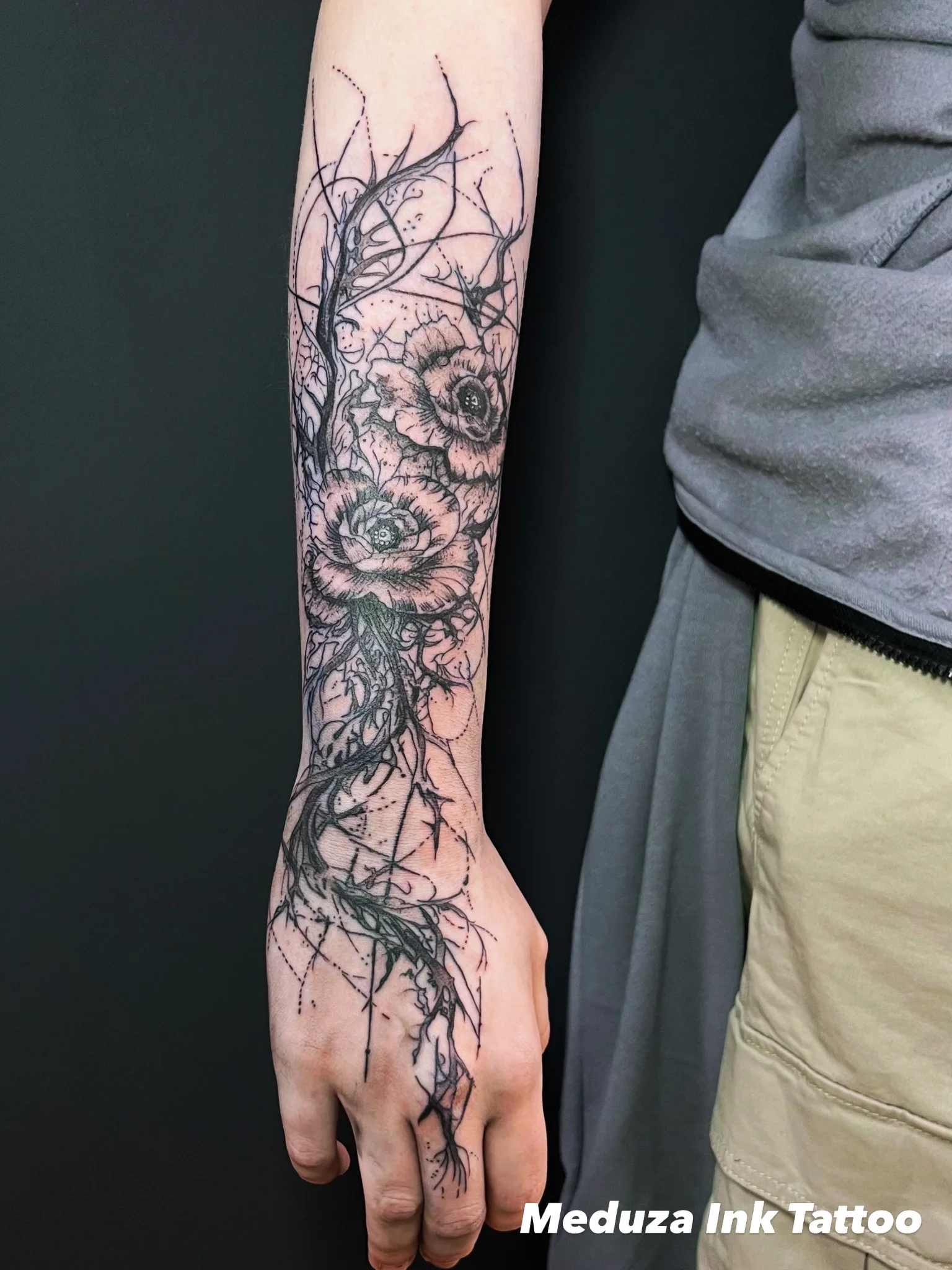 Fine line black floral and thorn tattoo on forearm and hand