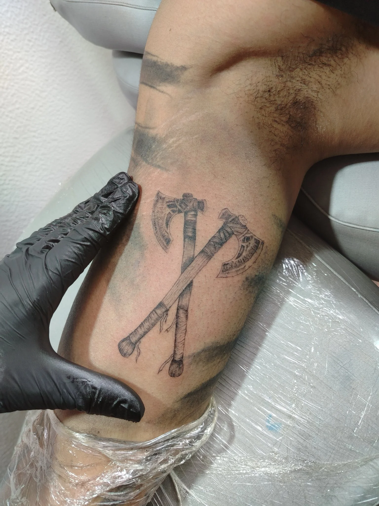 Black and grey crossed Viking axes tattoo on knee area