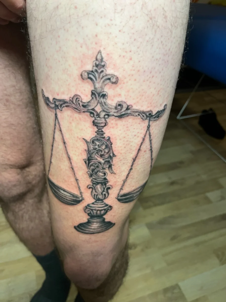Neo-traditional scales of justice tattoo on lower leg
