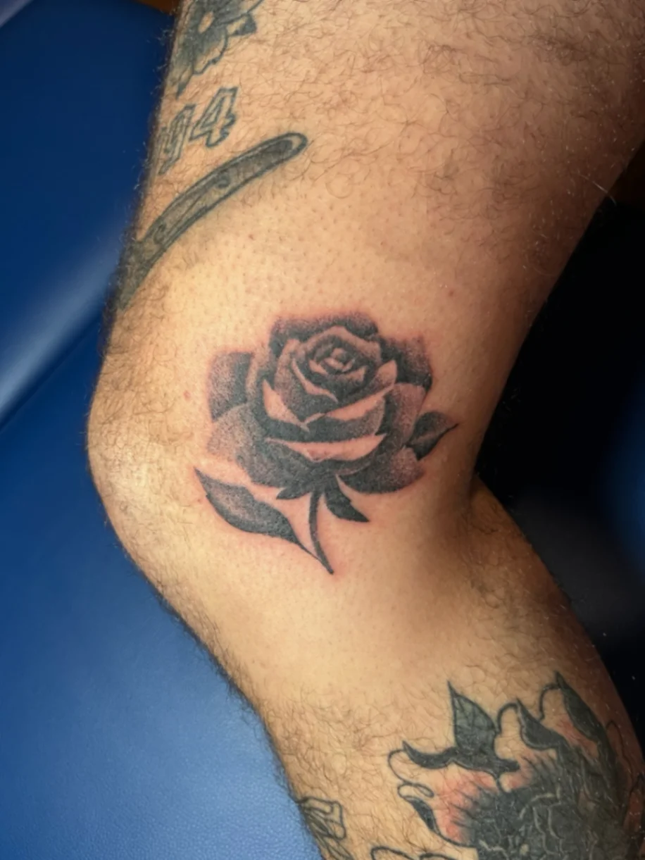 Black and grey rose tattoo on the knee
