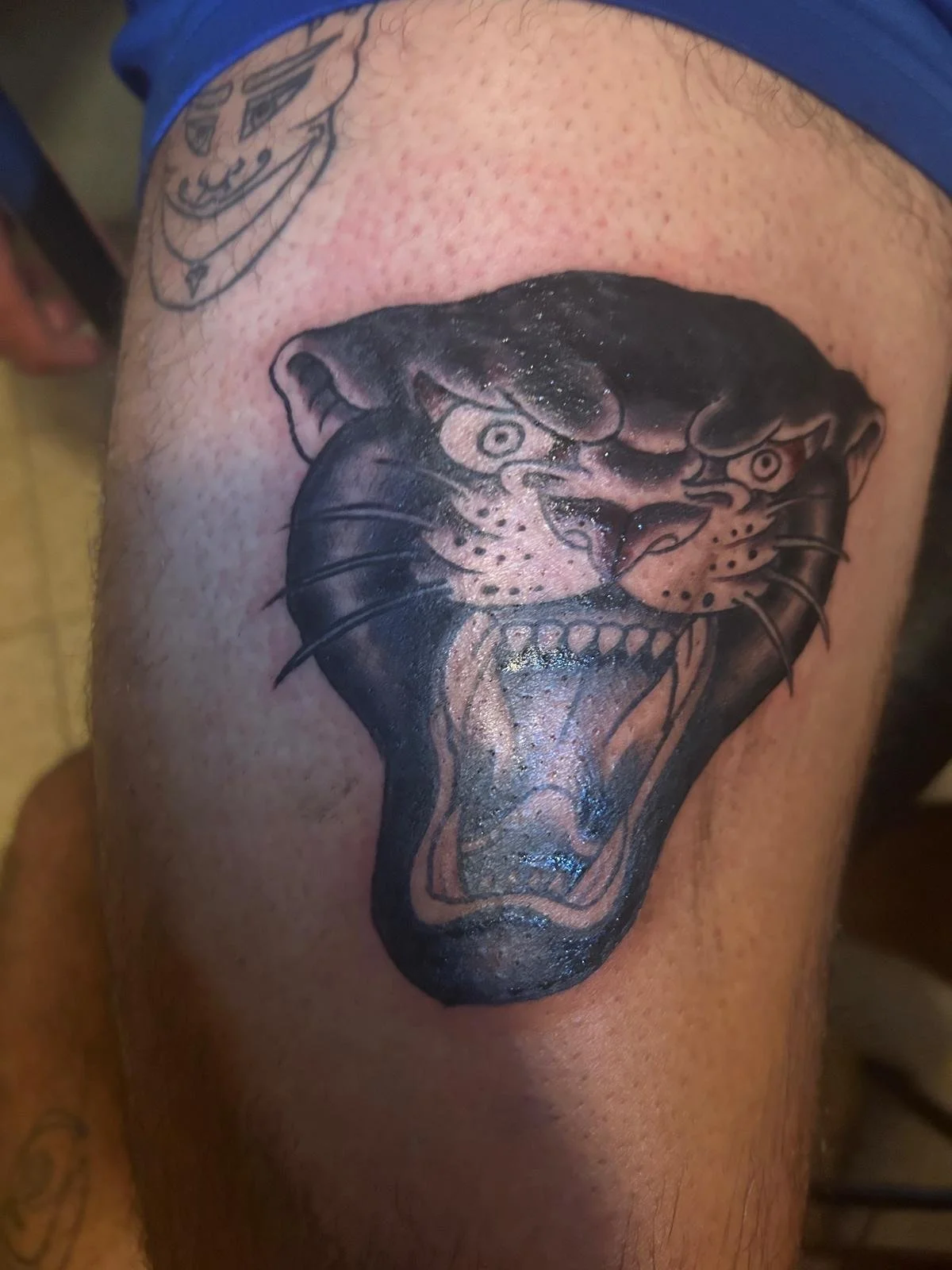 Neo-traditional black panther head tattoo on upper thigh