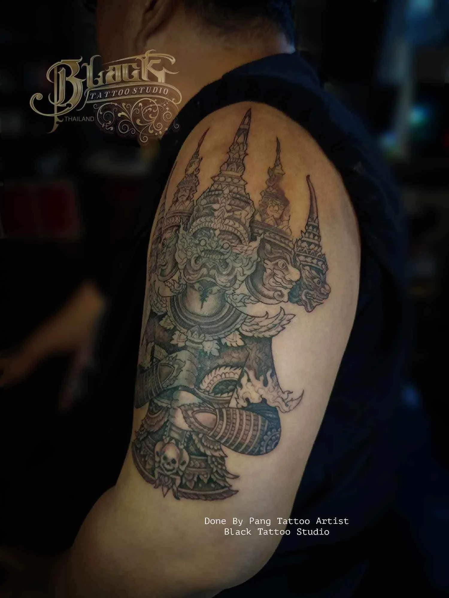 Black and grey Thai mythological figure tattoo on upper arm