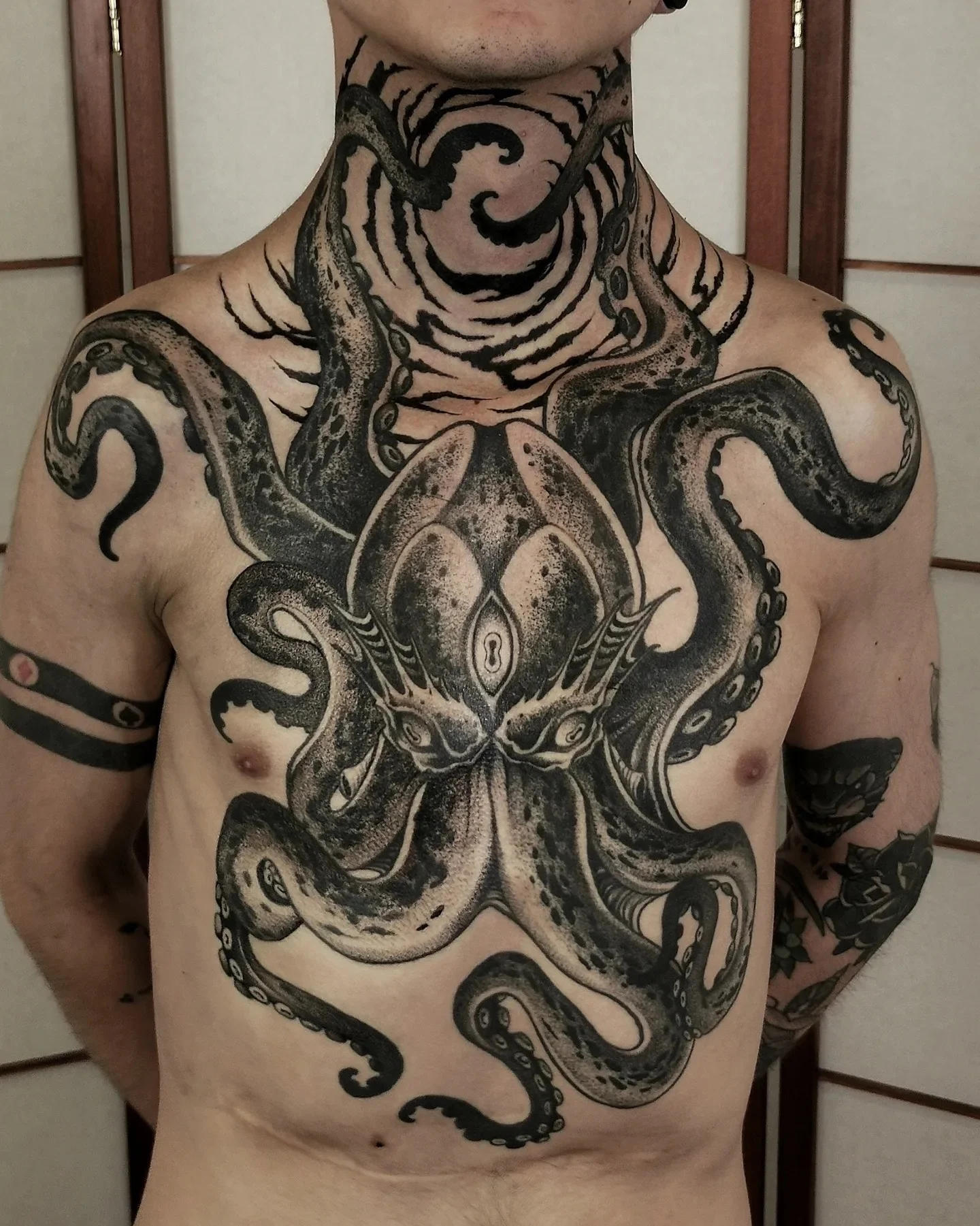 Black and grey realism octopus tattoo covering chest and neck