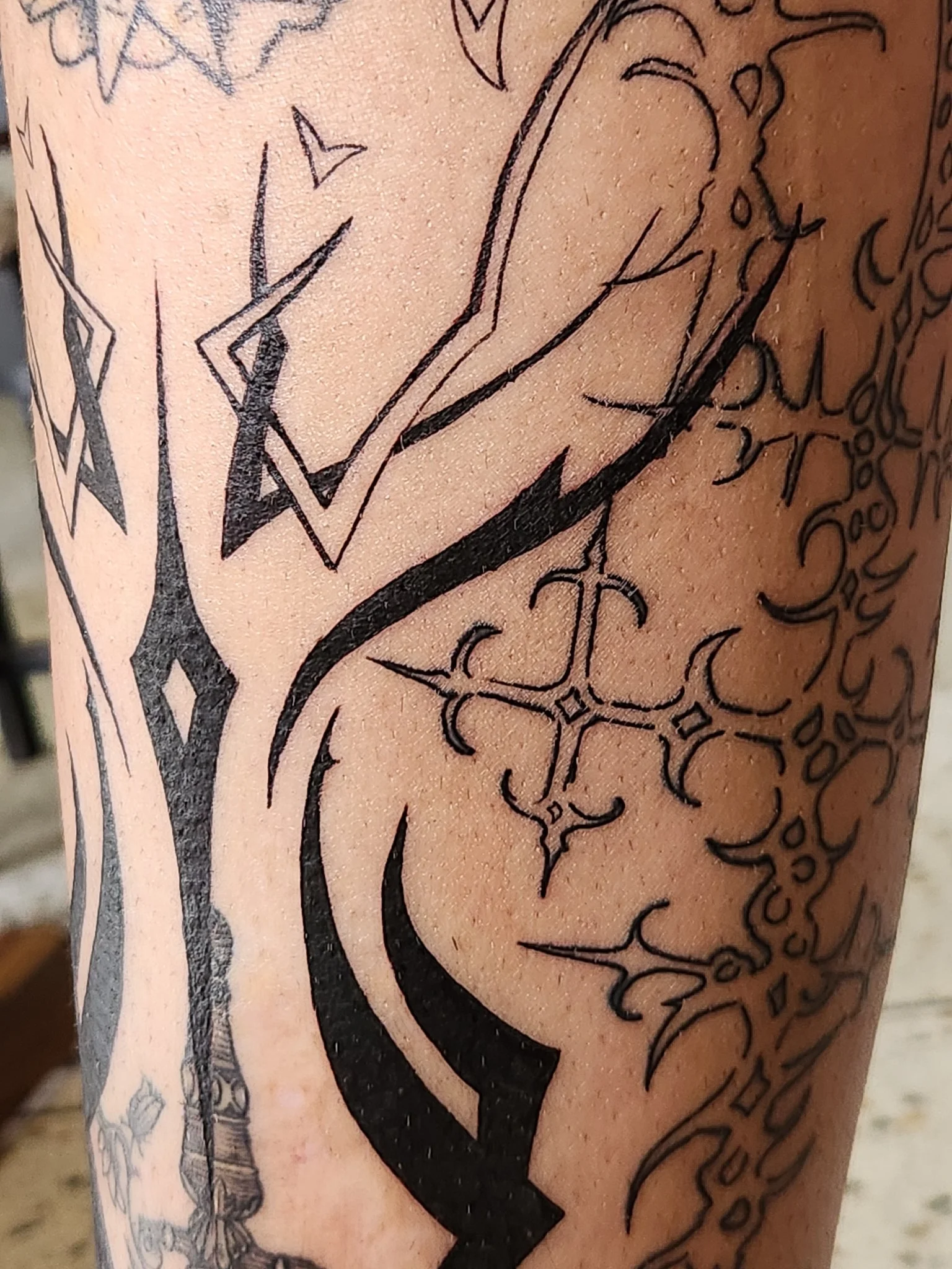 Blackwork sleeve with geometric symbols tribal shapes and ornamental cross