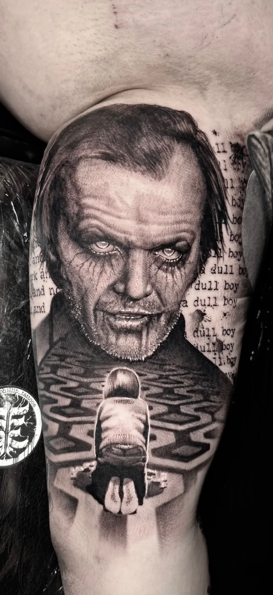 Black and grey realism Shining-themed portrait tattoo on upper arm