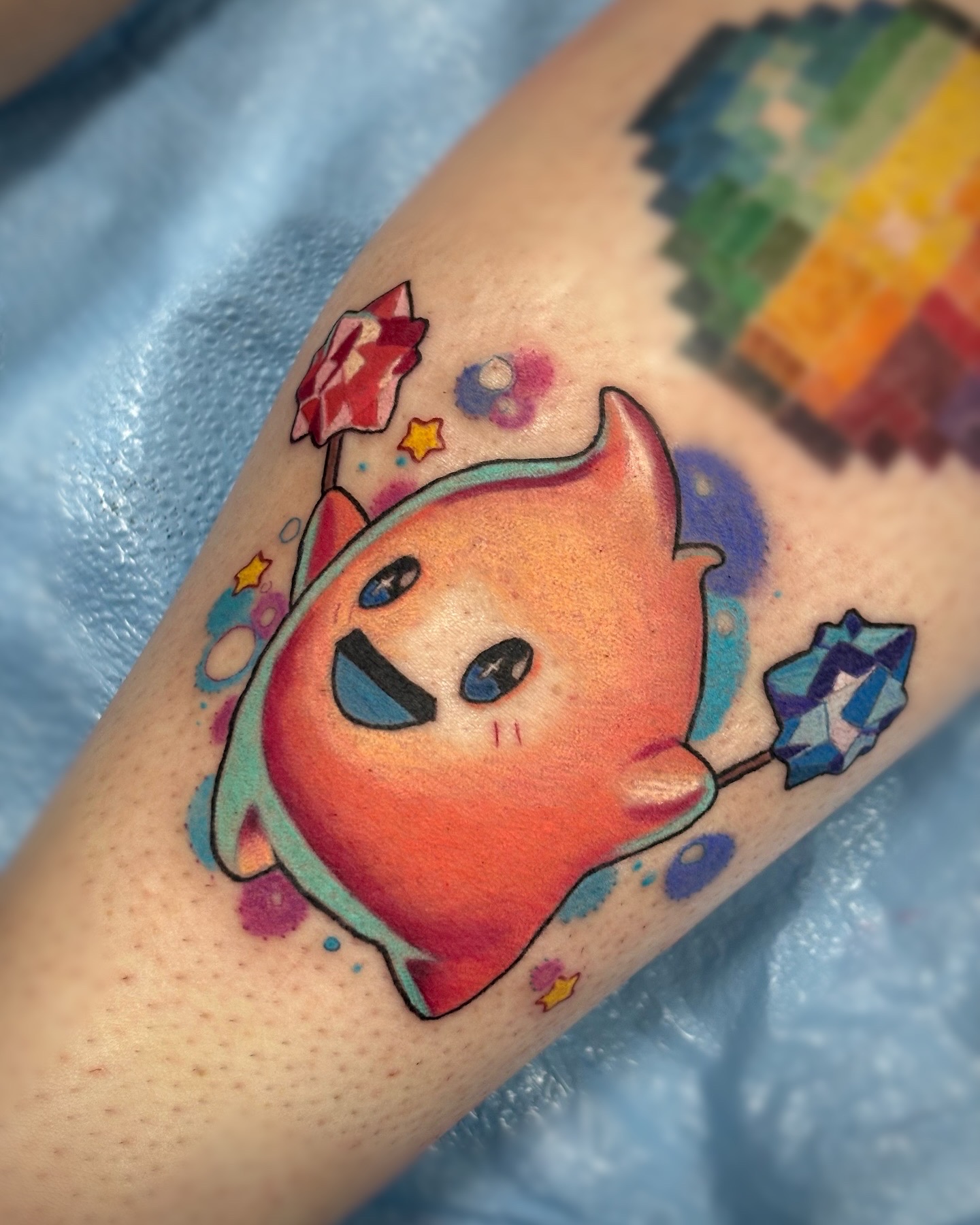 Colorful illustrative character tattoo with stars and sparkles on forearm