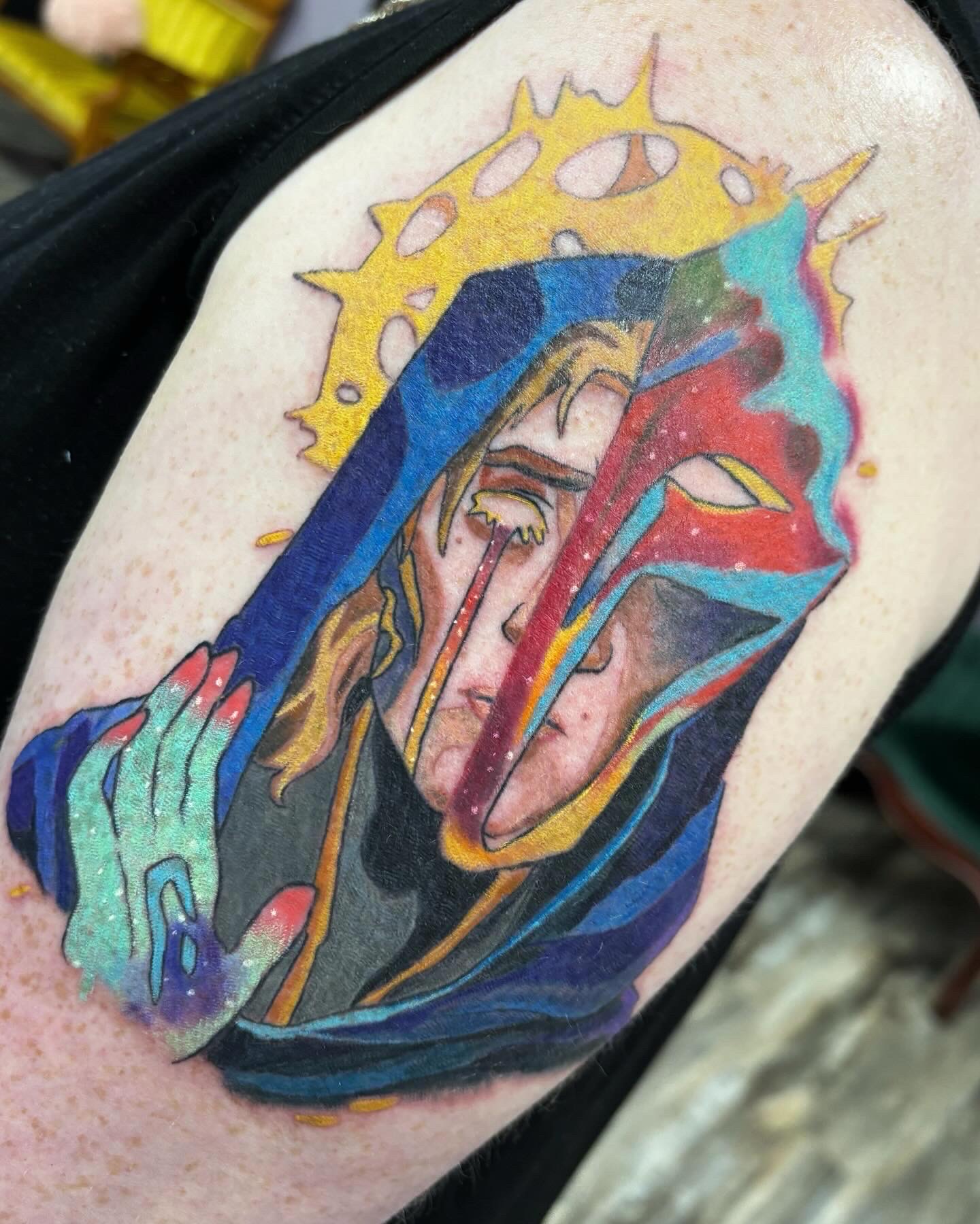 Colorful surreal portrait tattoo featuring multiple overlapping faces on upper arm