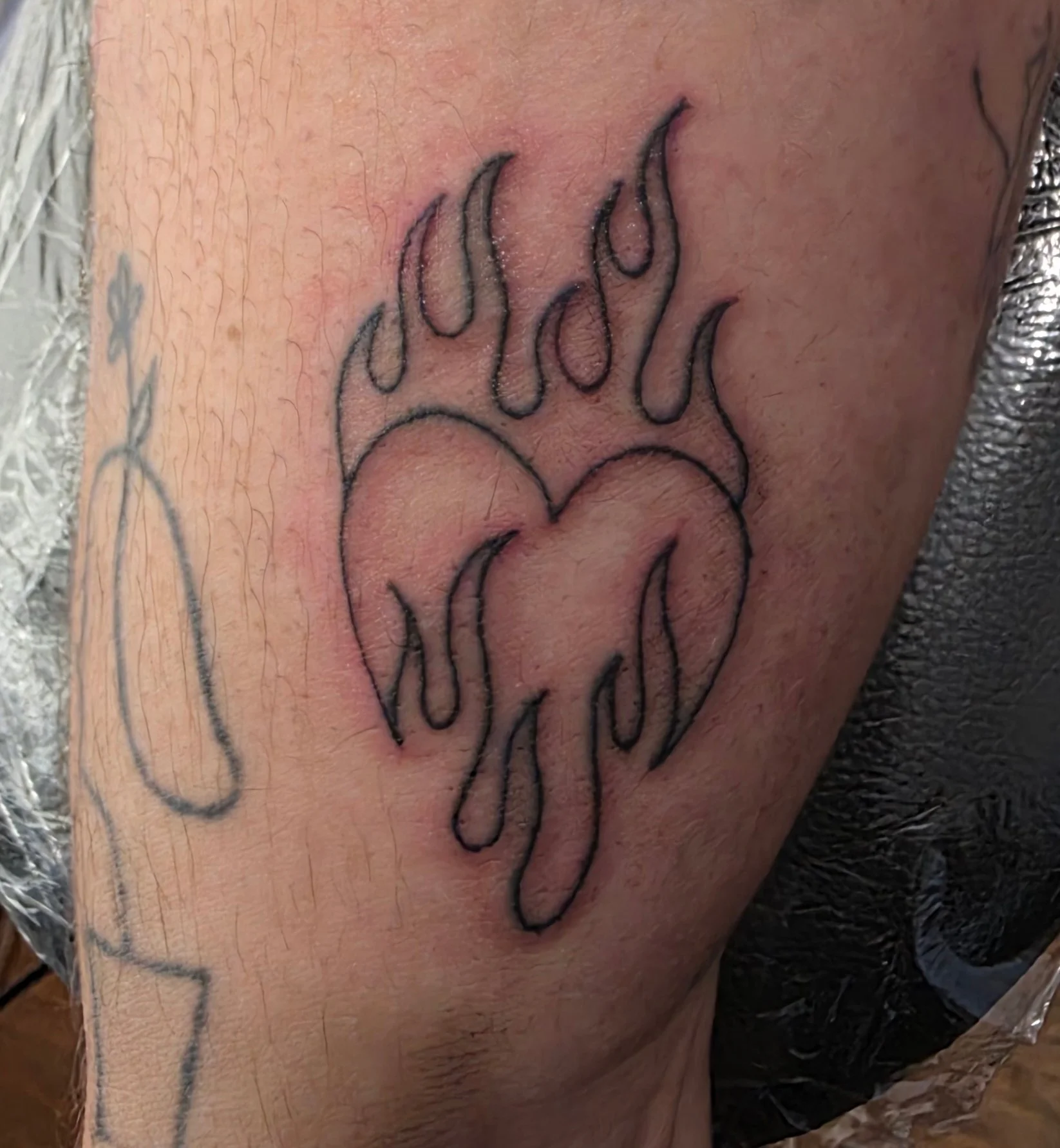 Flaming dripping heart outline tattoo on lower leg