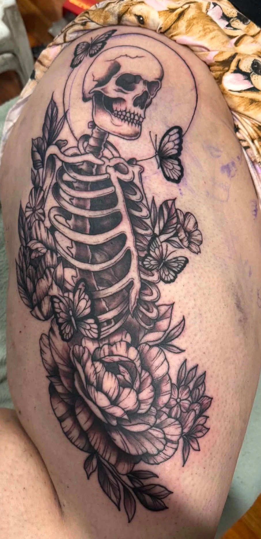 Black and grey skeleton with butterflies and florals on thigh