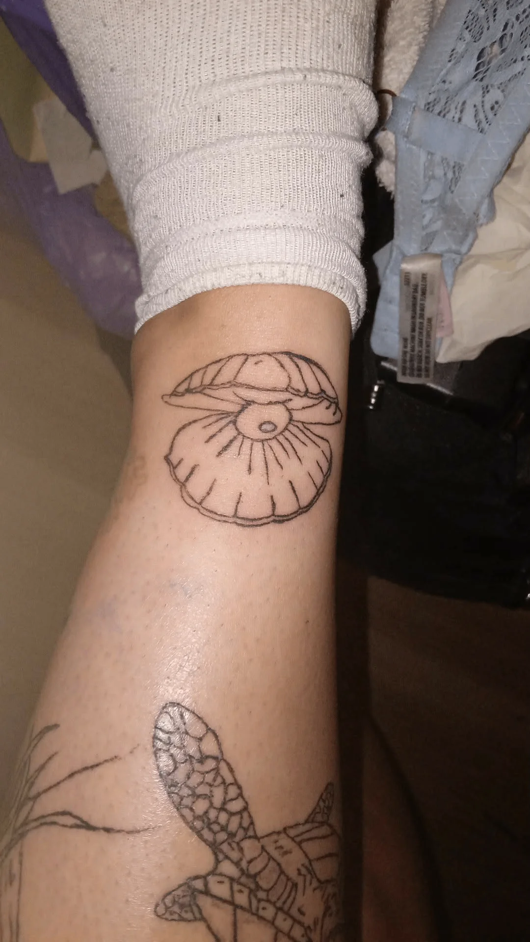 Fine line open clam shell with pearl tattoo on forearm