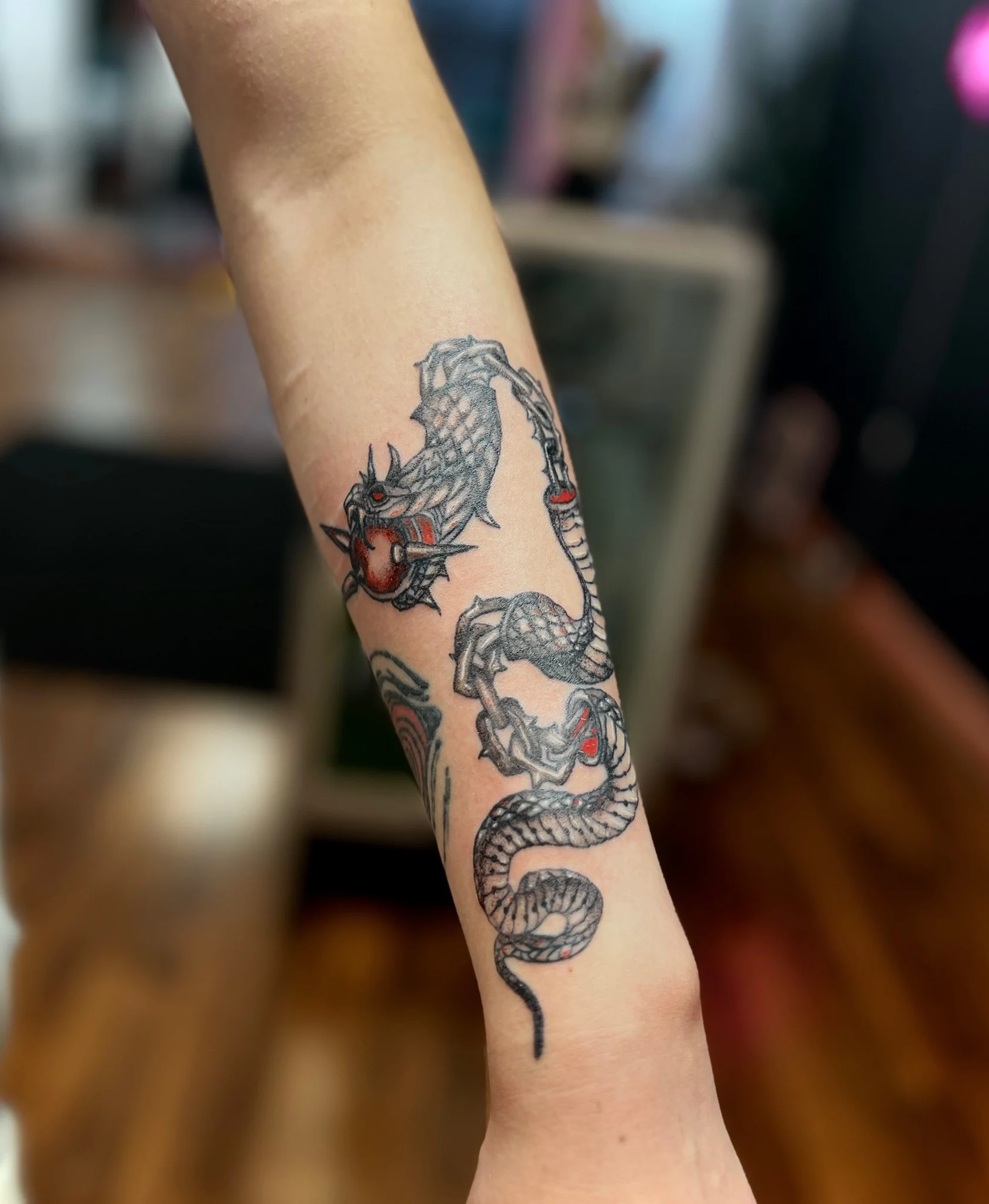 Japanese style dragon and snake tattoo on forearm with red accents