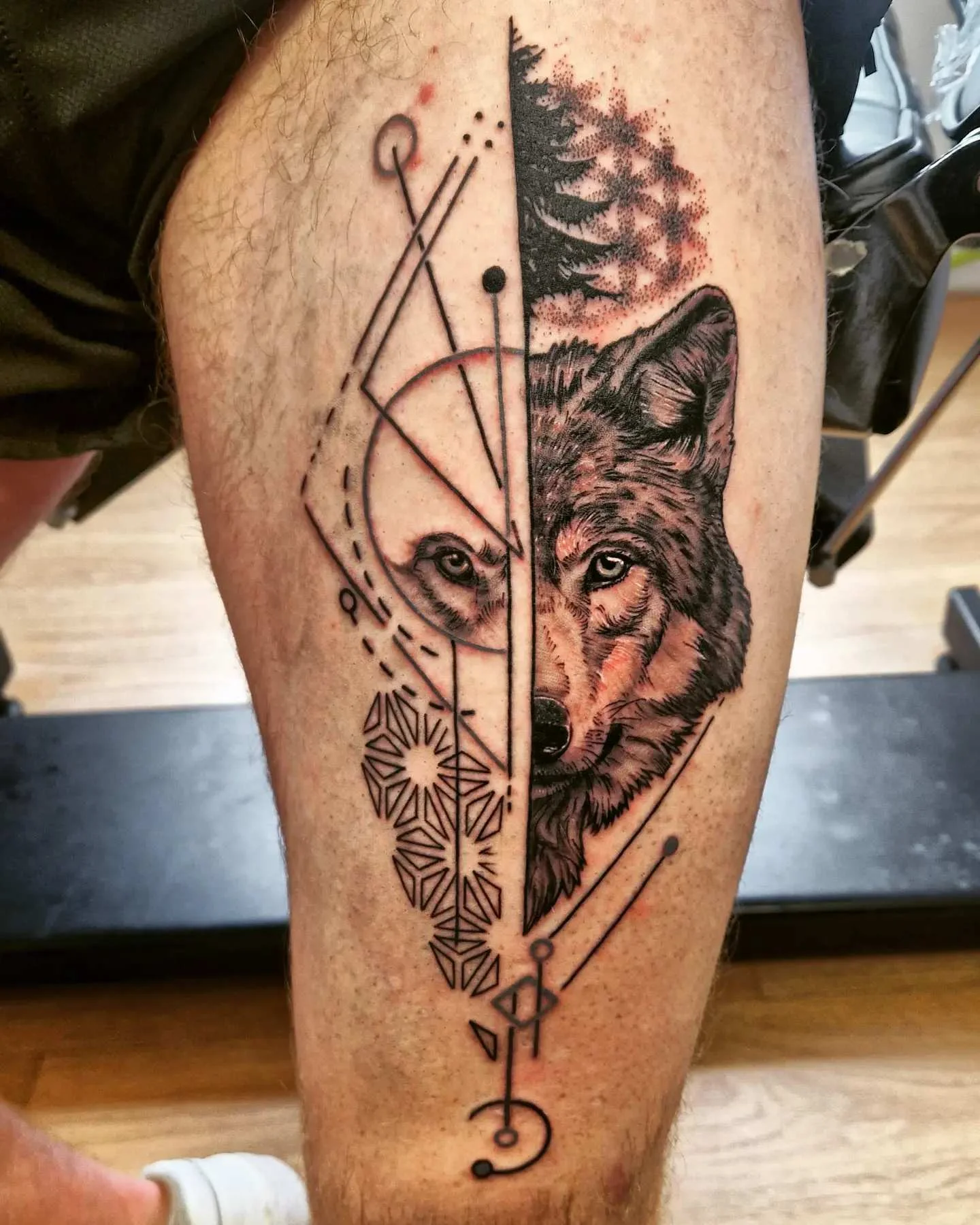 Split geometric and realism wolf tattoo on lower leg