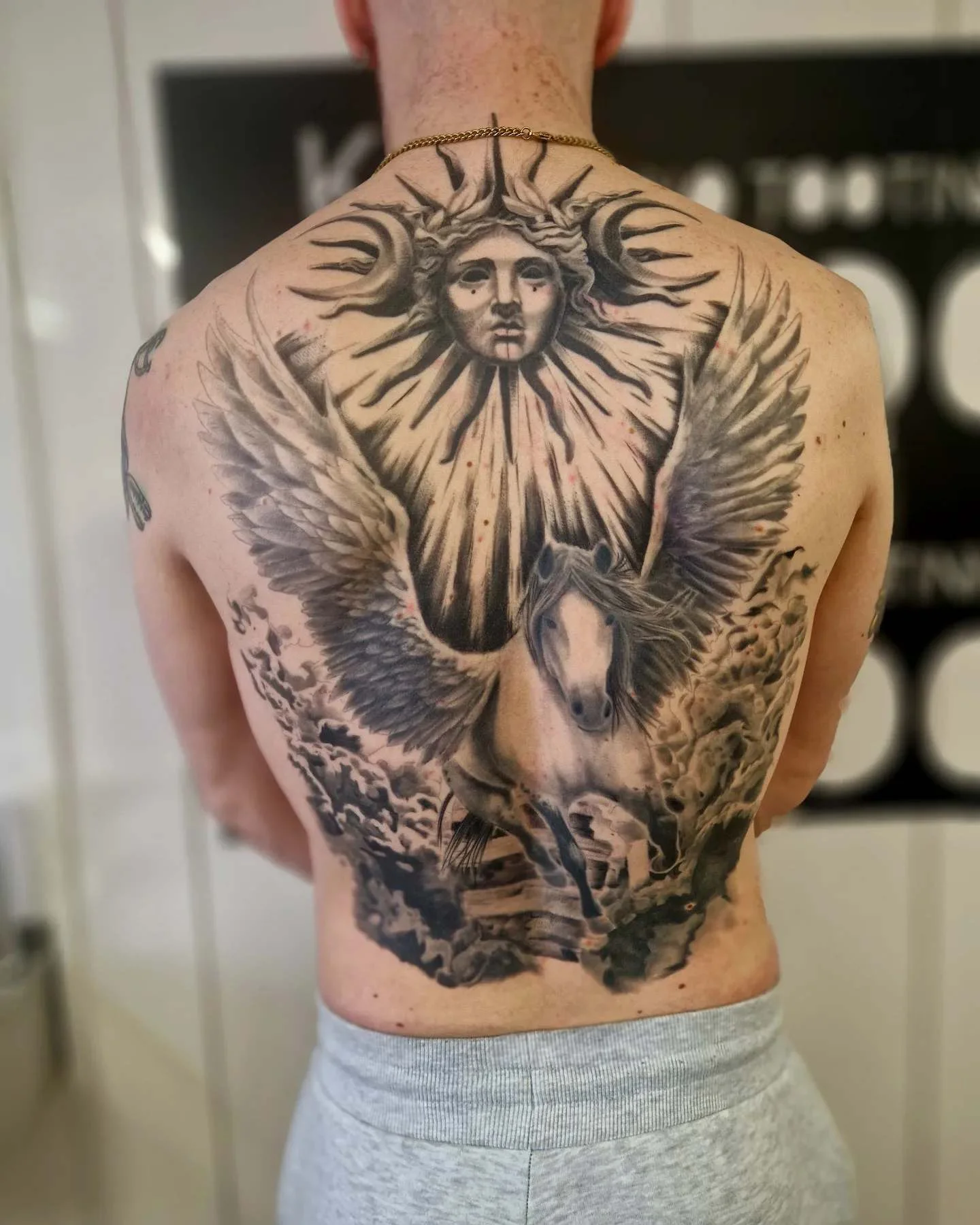 Black and grey realism Pegasus and sun deity full back tattoo