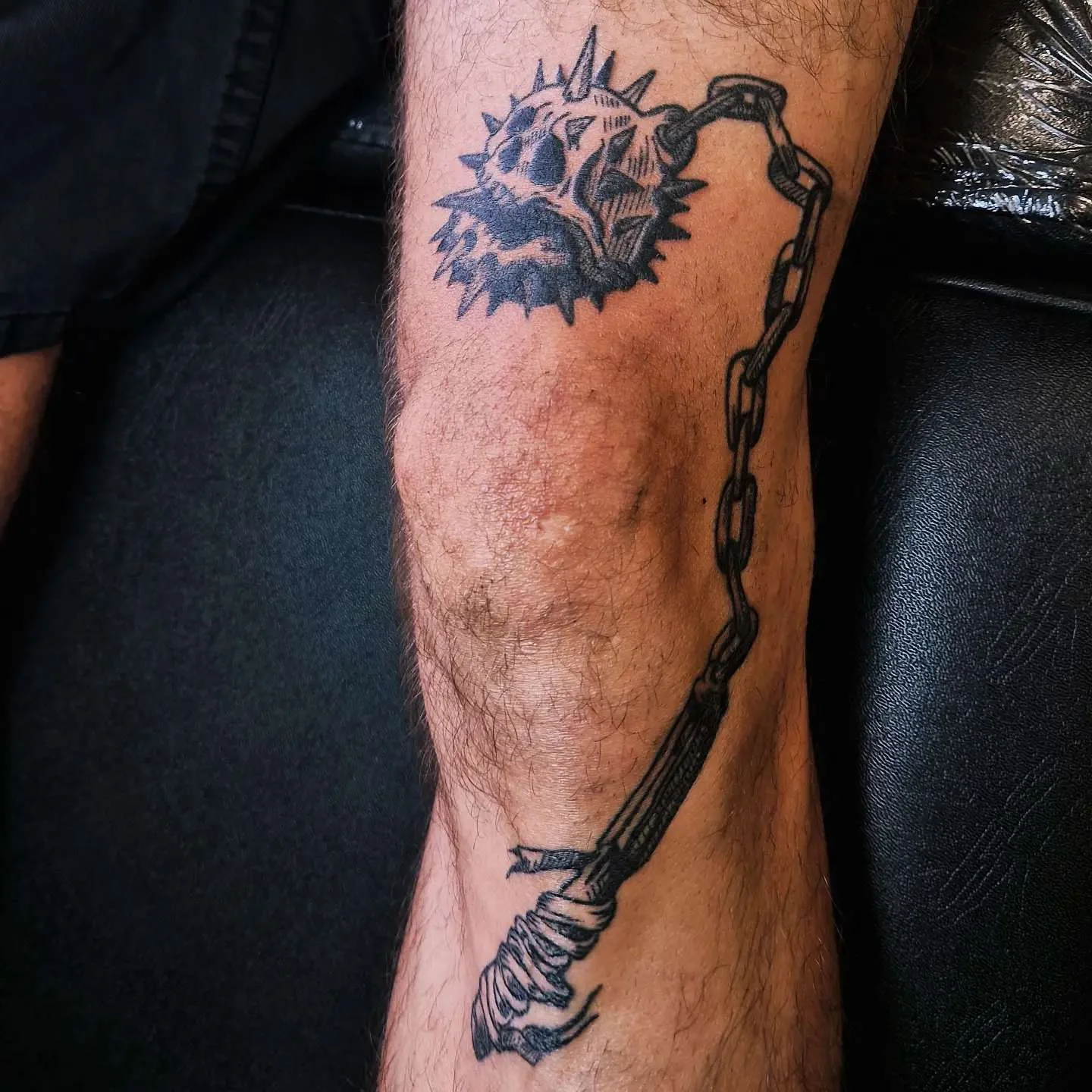 Black illustrative flail with skull and skeleton hand tattoo on leg