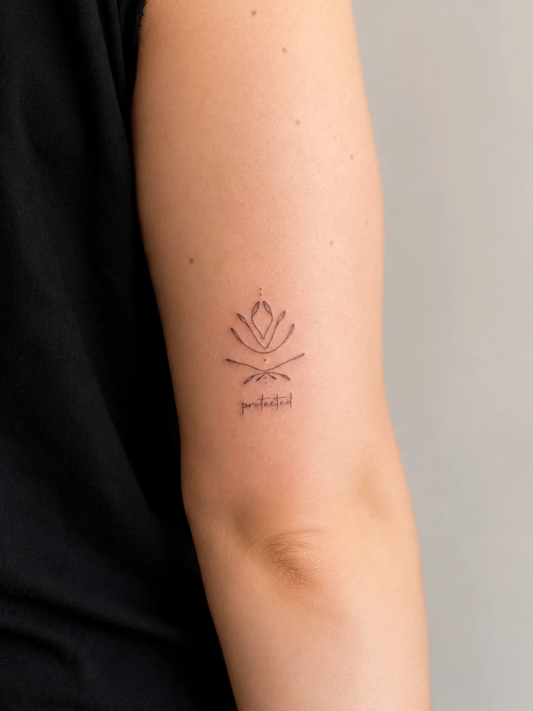 Fine line lotus and crossed arrows tattoo with 'protected' script on upper arm