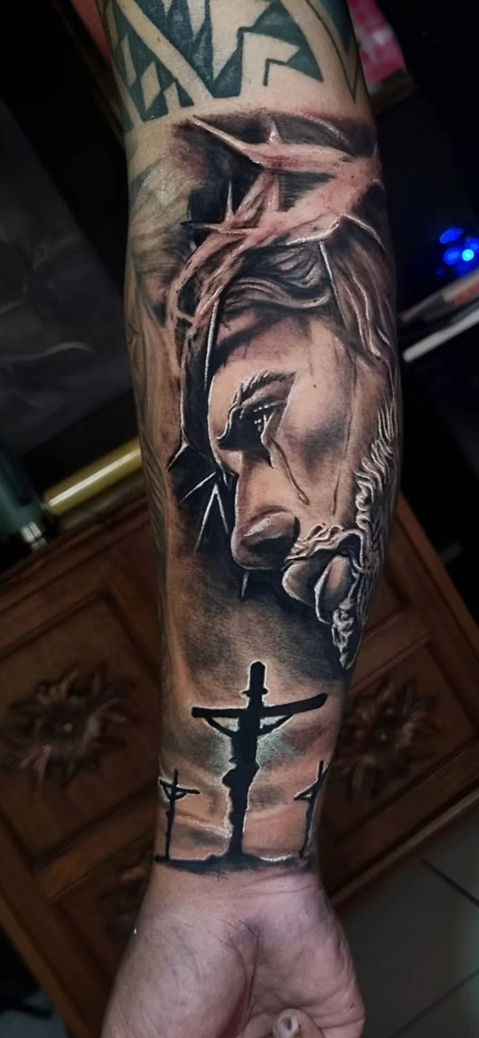 Black and grey realism Jesus with crown of thorns and crucifixion scene on forearm