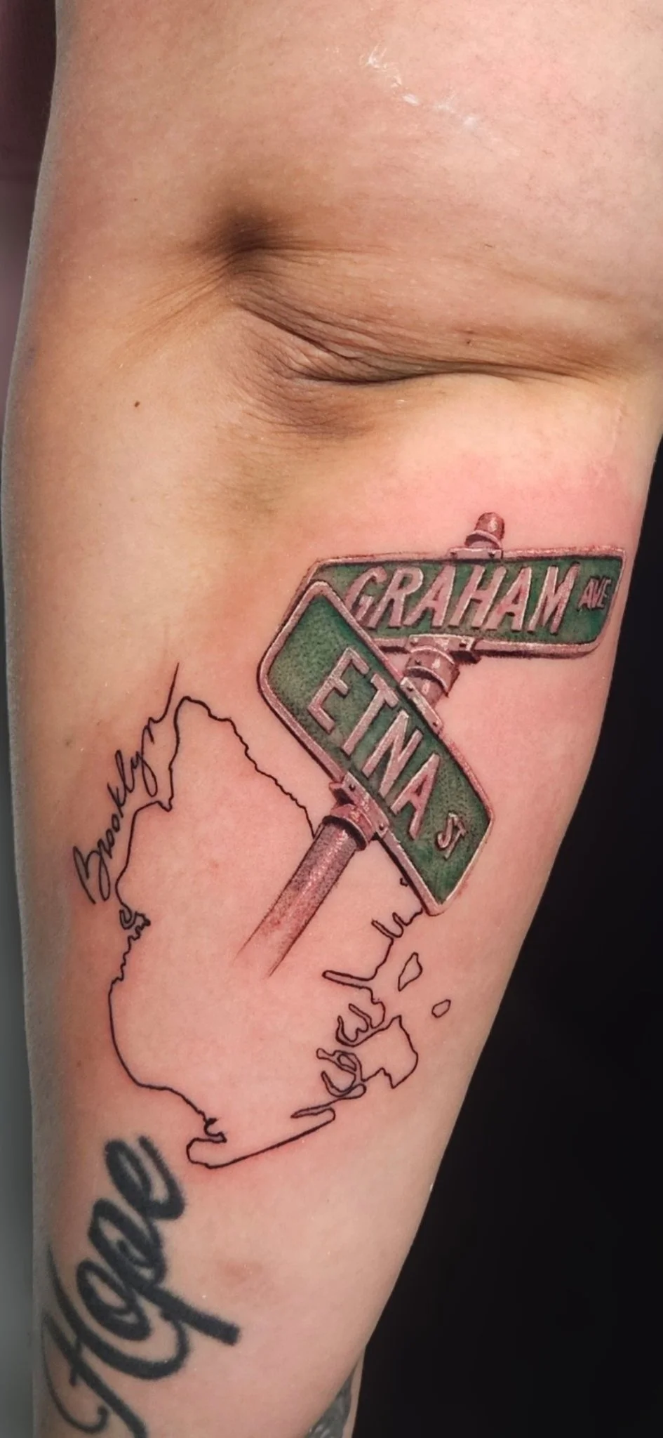 Color realist street sign tattoo with borough map outline on forearm