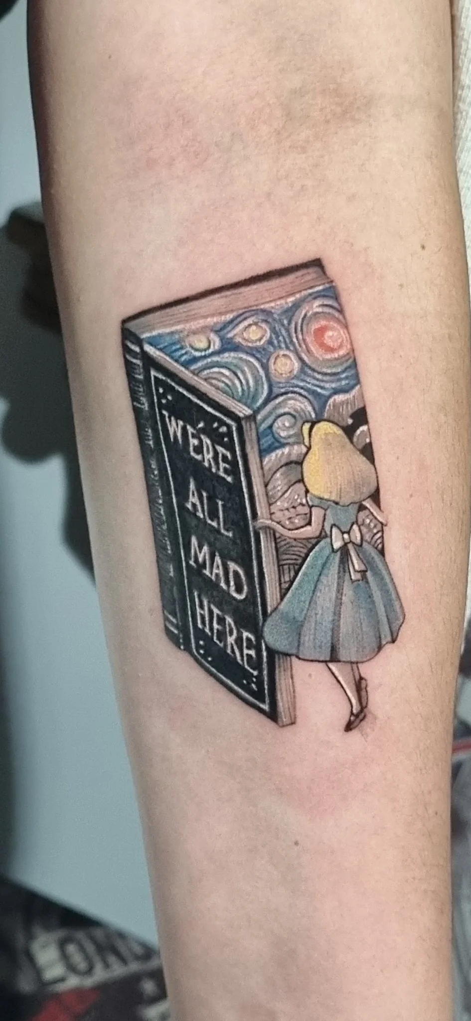 Color neo-traditional Alice in Wonderland book tattoo on forearm