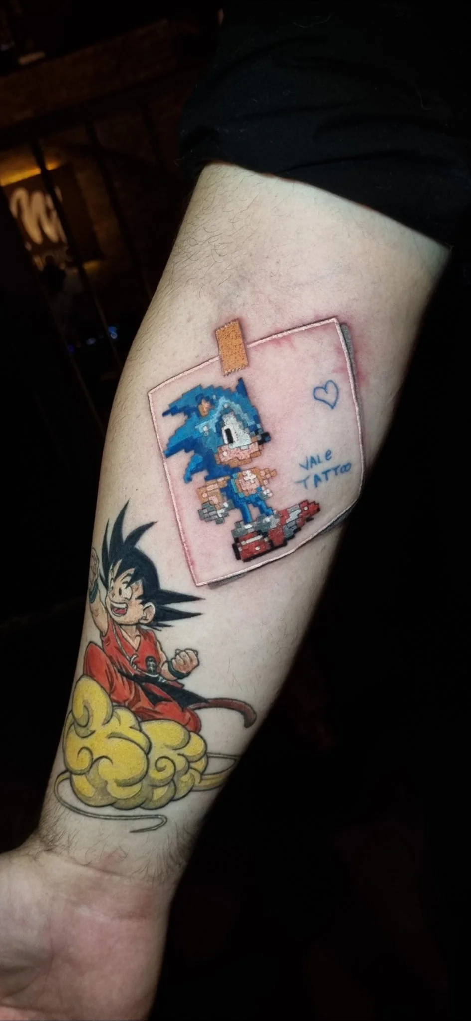 Patchwork forearm tattoo featuring pixel Sonic and young Goku on flying nimbus