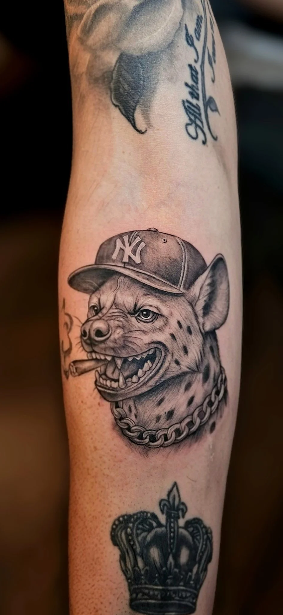 Black and grey realism hyena with NY cap and chain on forearm