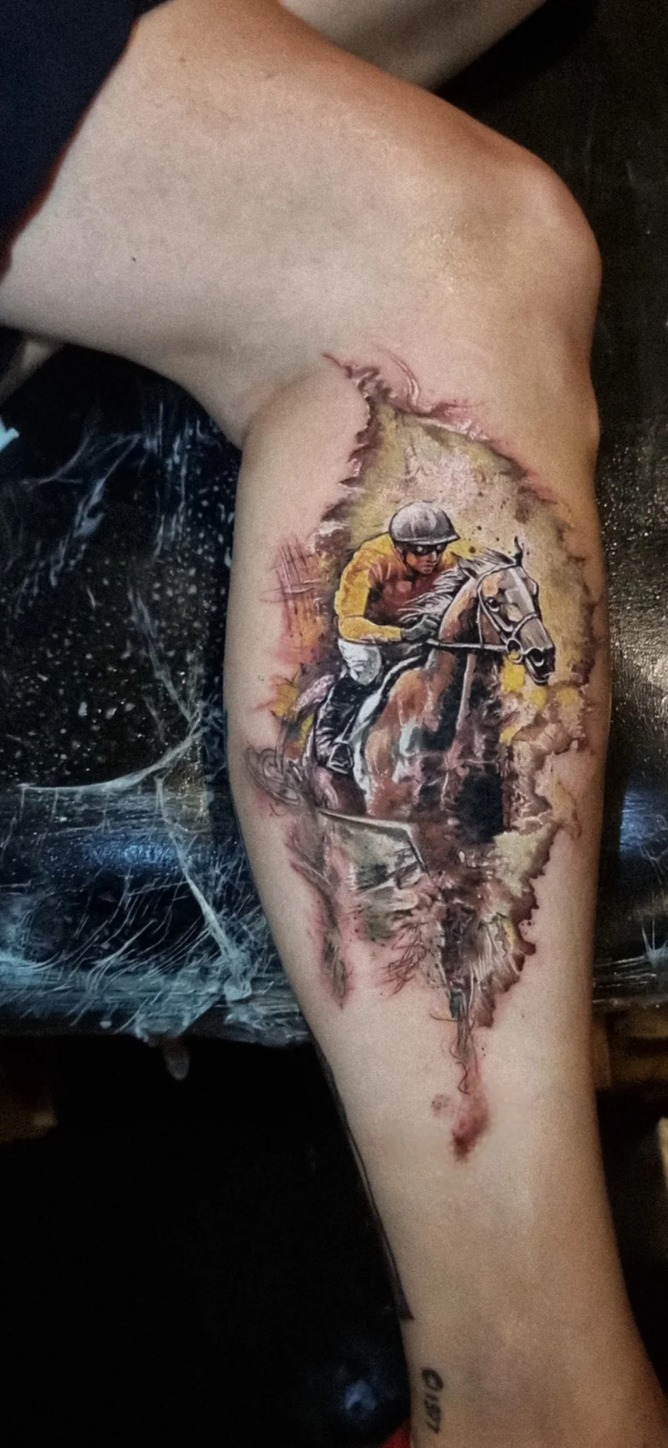 Watercolor style horse racing jockey tattoo on forearm