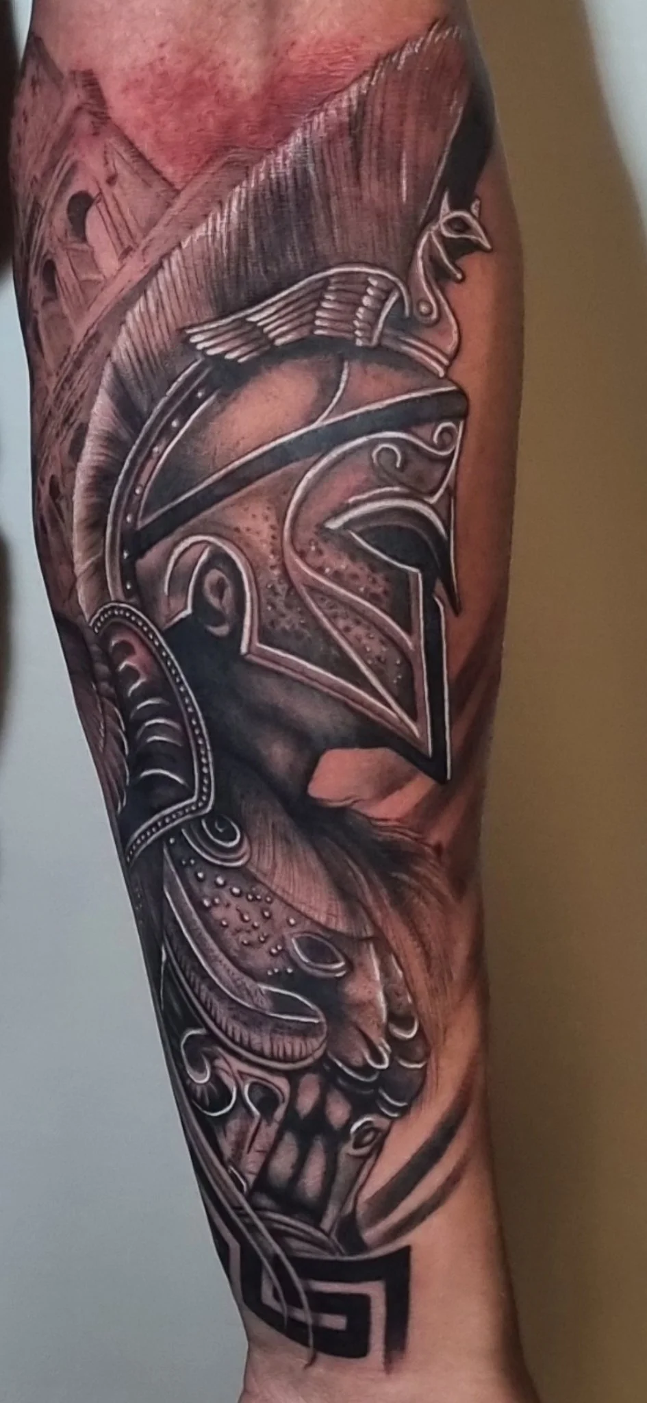 Black and grey realism Spartan helmet and armor tattoo on forearm