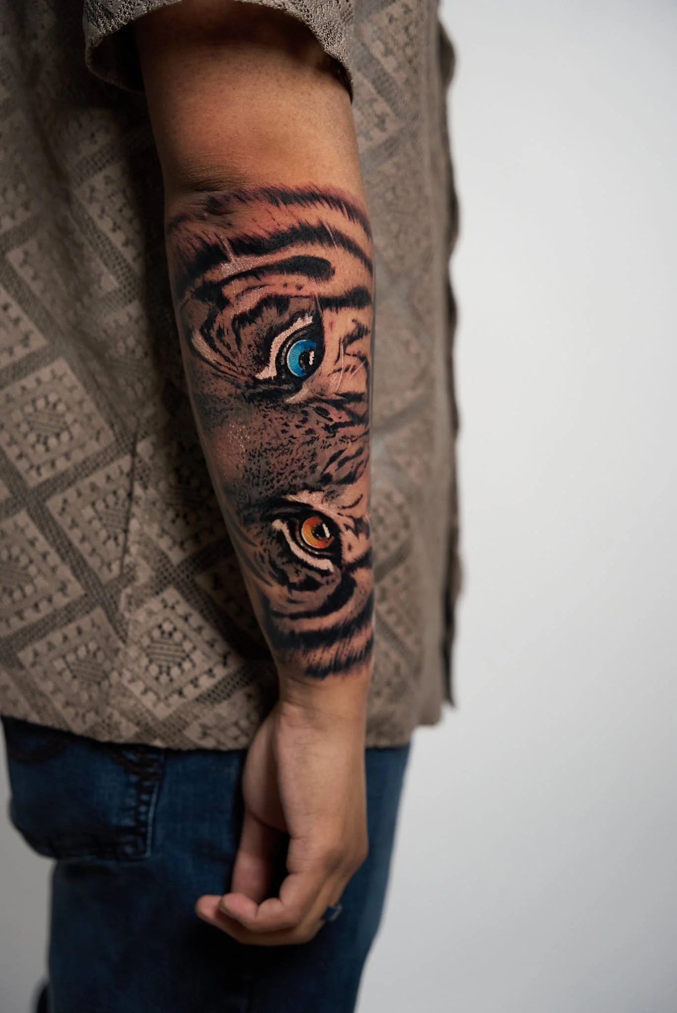 Color realism tiger eyes tattoo with blue and amber irises on forearm