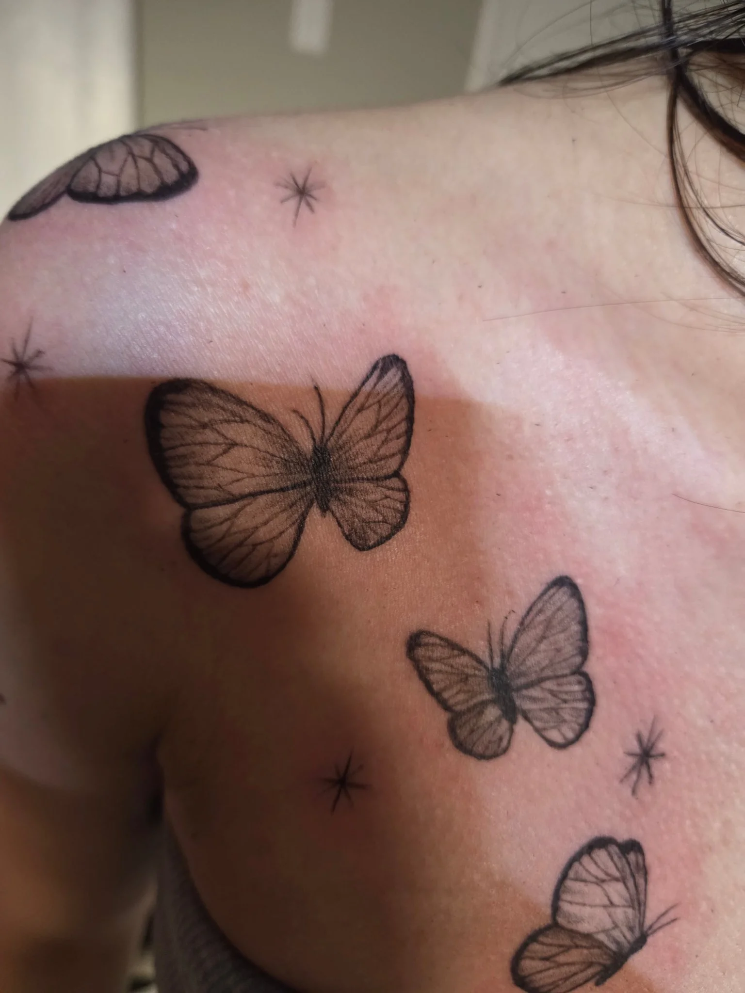 Fine line black and grey butterfly scatter tattoo on shoulder and back