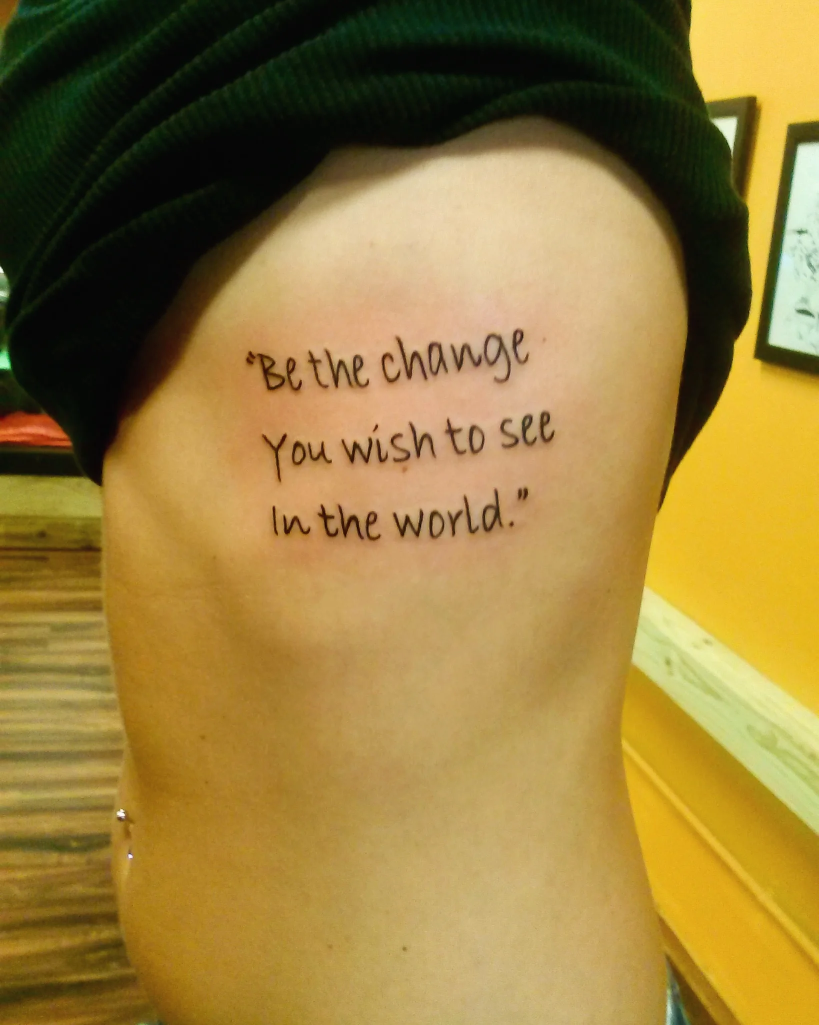 Script quote tattoo on the ribcage in black ink