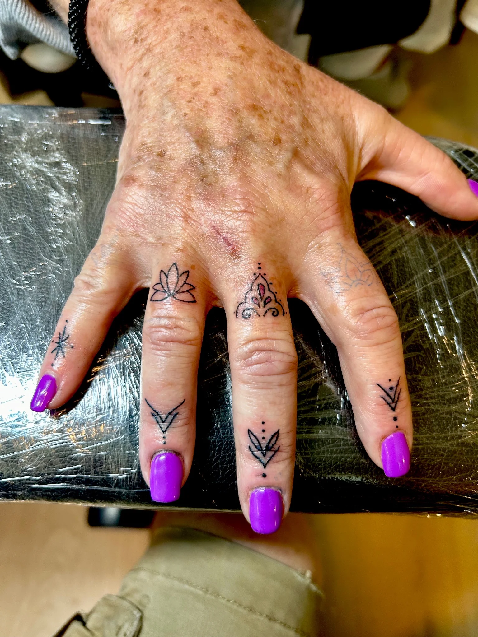 Fine line ornamental finger tattoos with lotus and mandala motifs