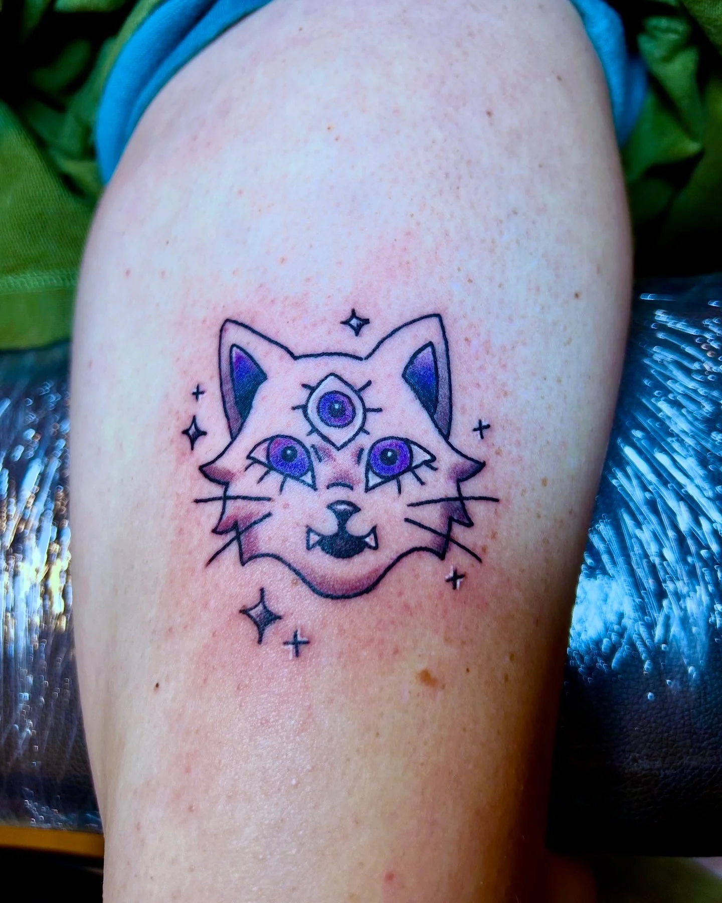 New school three-eyed mystical cat face tattoo on thigh