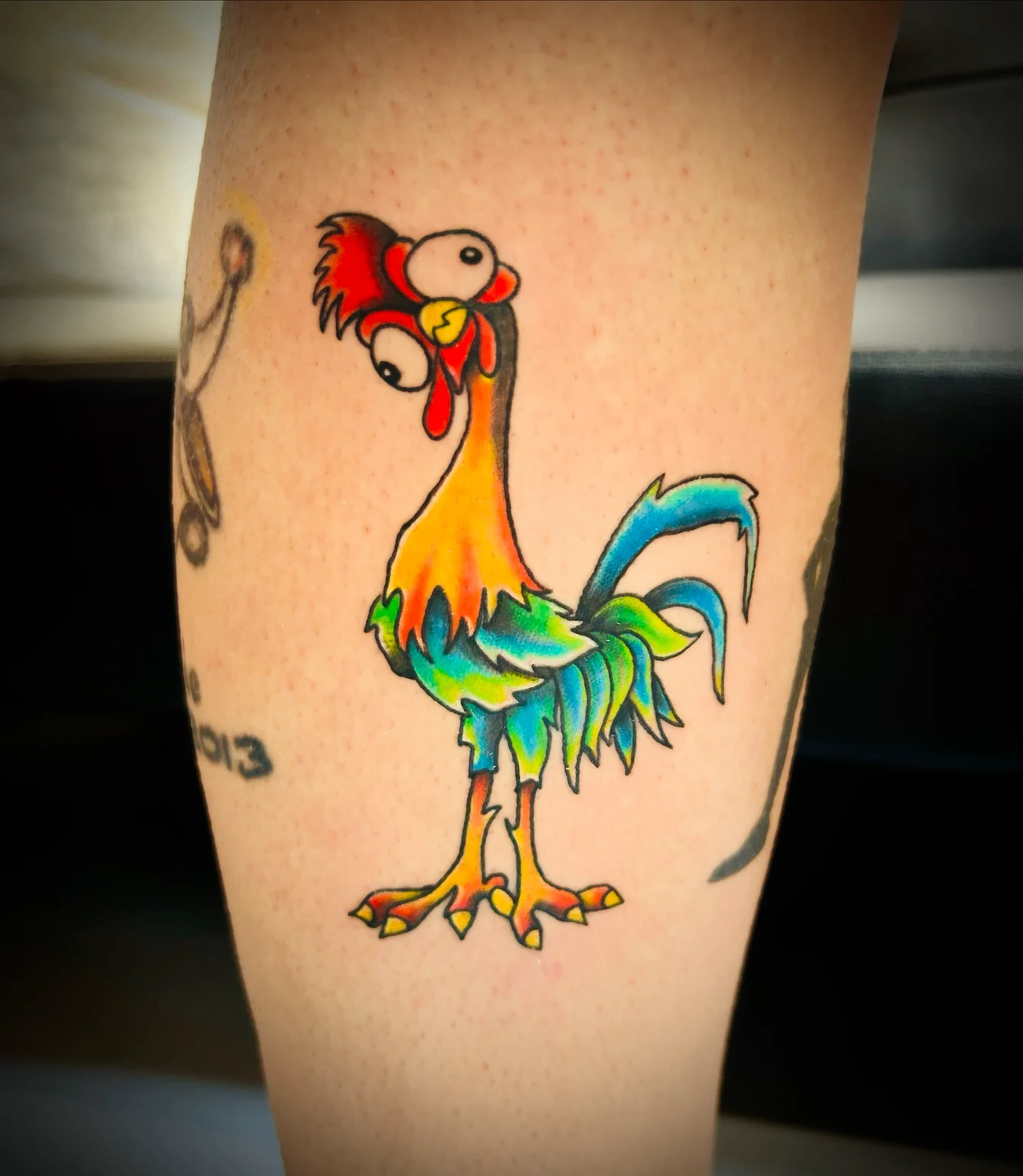 Colorful cartoon rooster character tattoo on lower leg